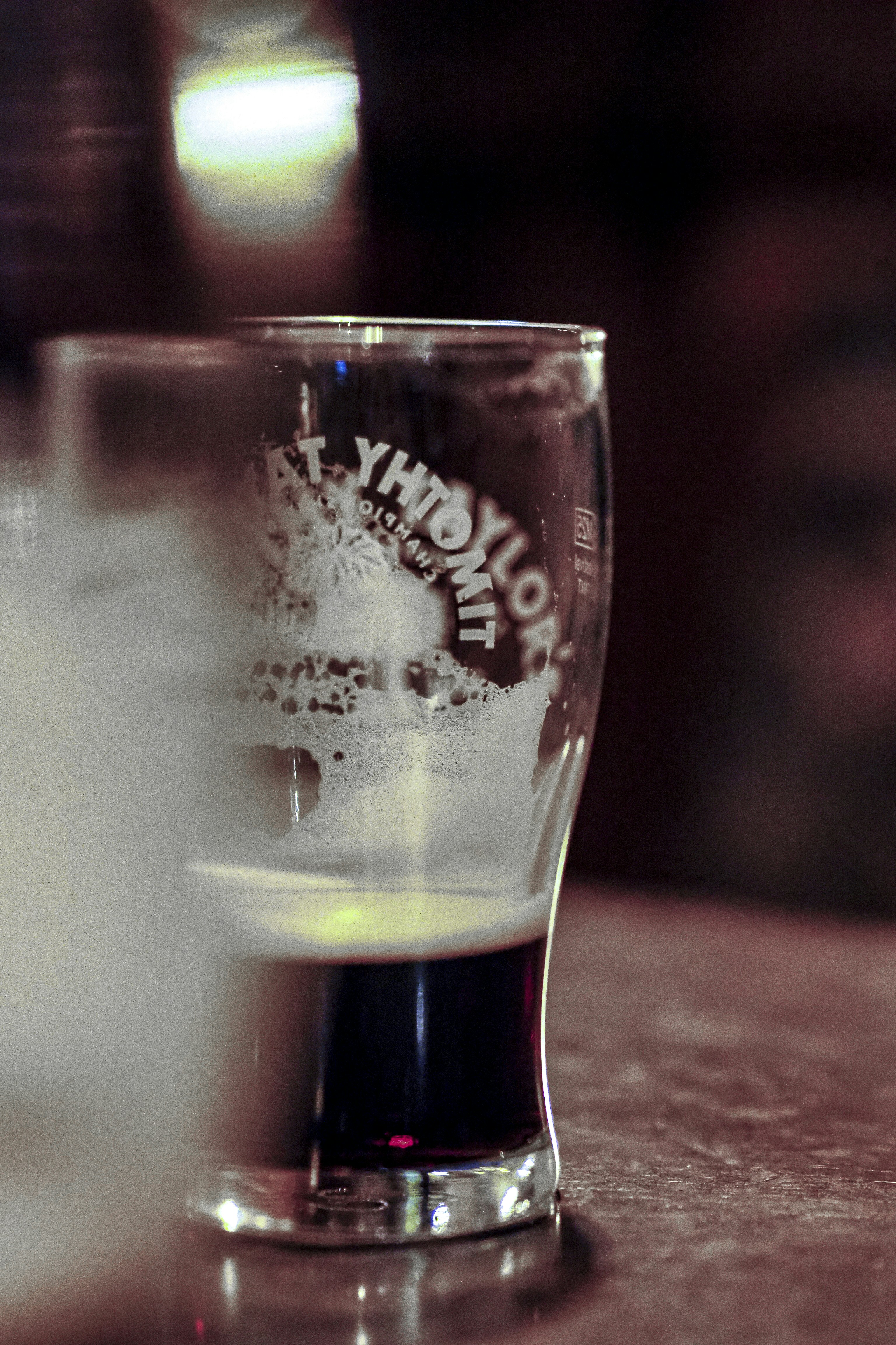 Un bicchiere di birra scura parzialmente consumato su un tavolo.