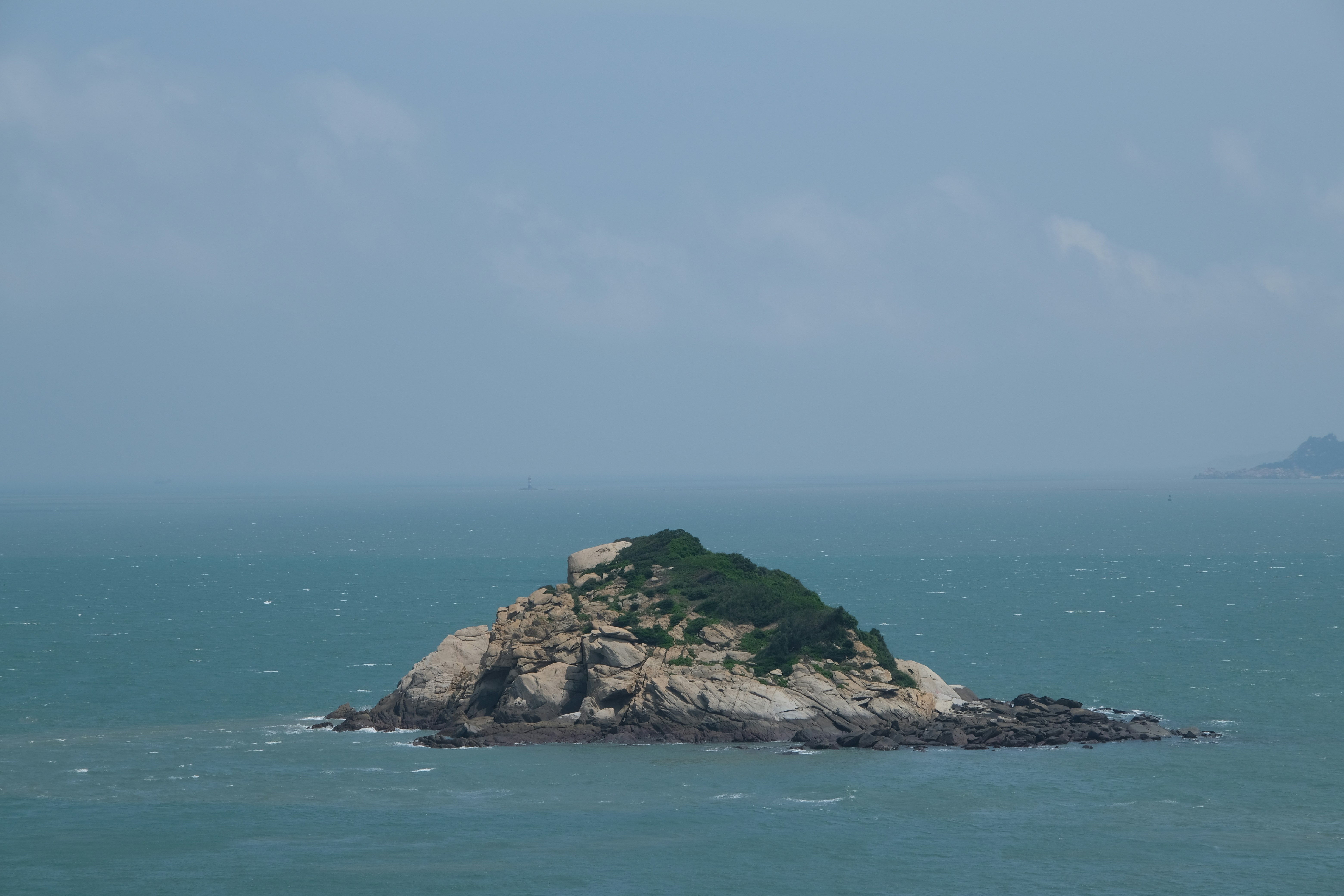 A small rocky island with green vegetation in the ocean