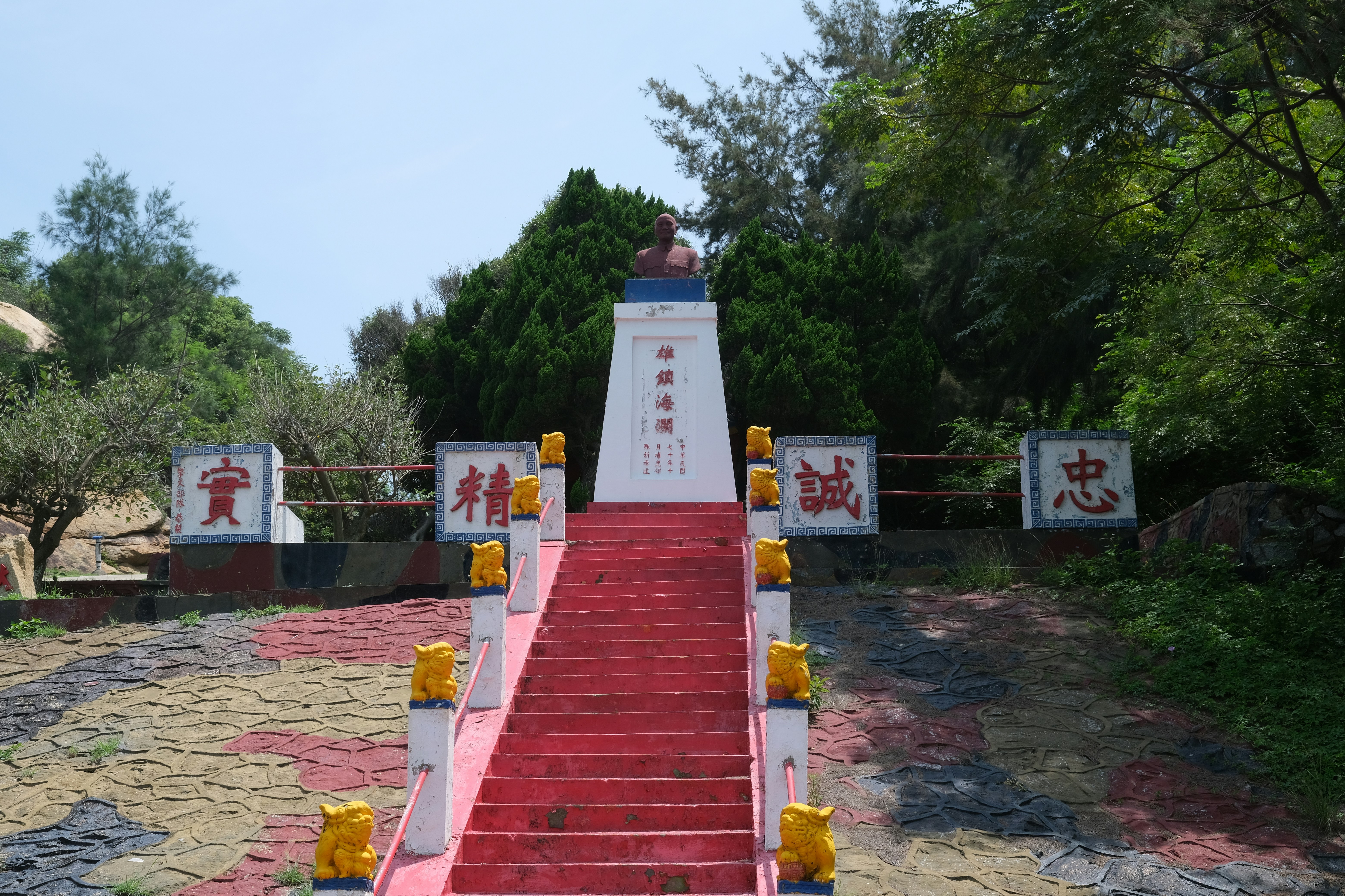 Red stairs ascend to a monument surrounded by trees