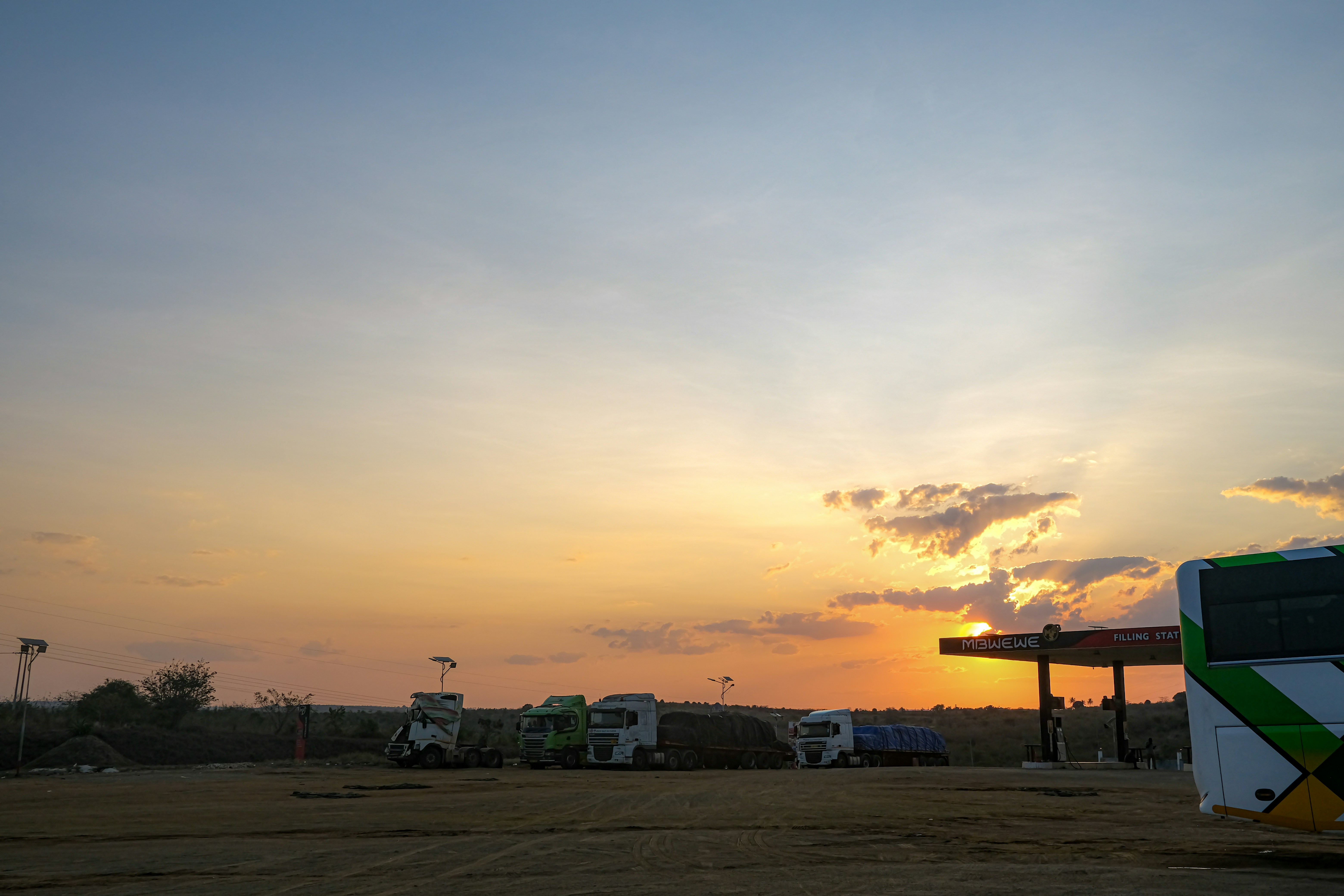 Sunset over a rest stop with a bus and trucks.