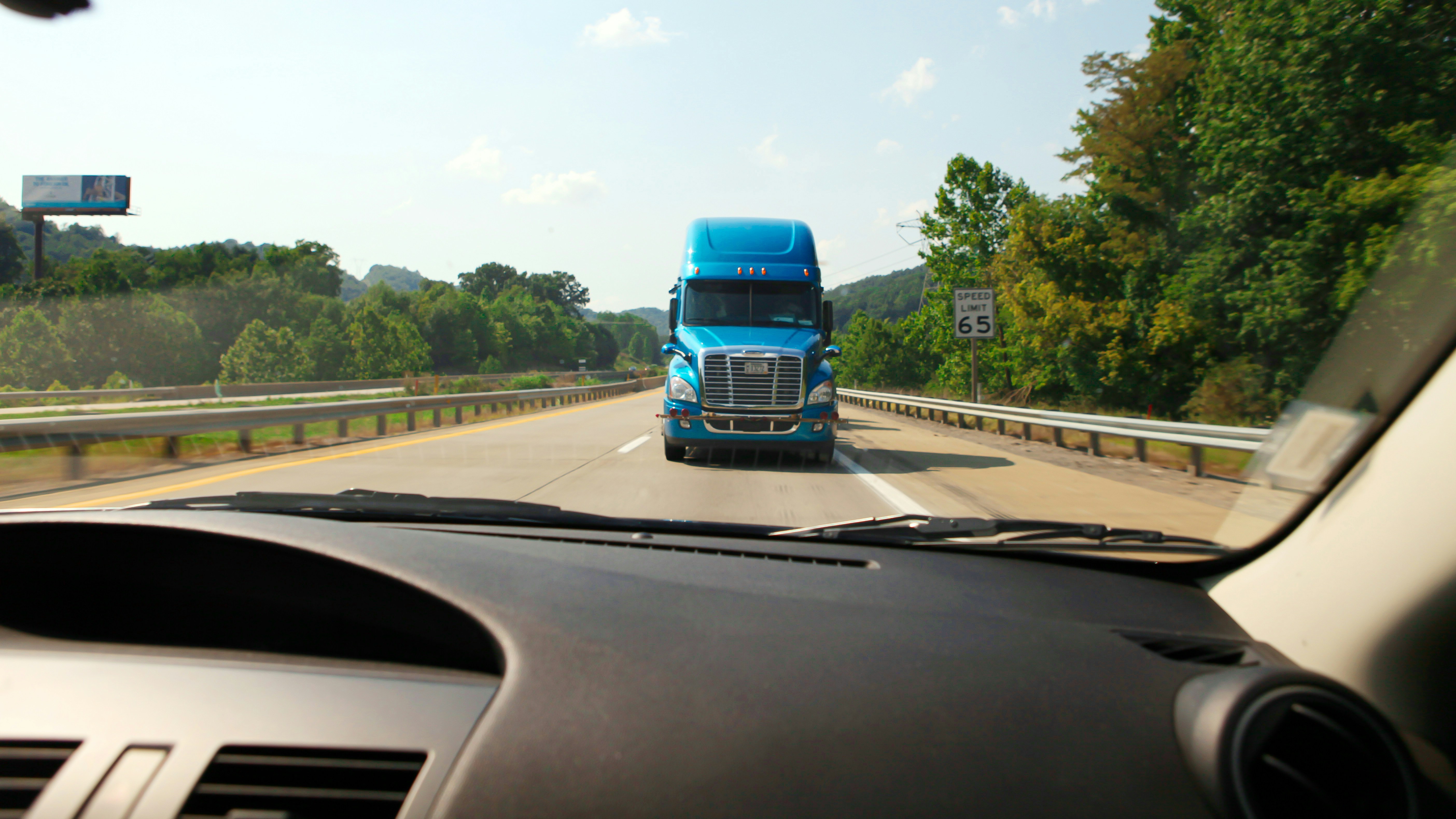Blauer Sattelzug, der aus der Perspektive eines Autos auf einer Autobahn nähert.