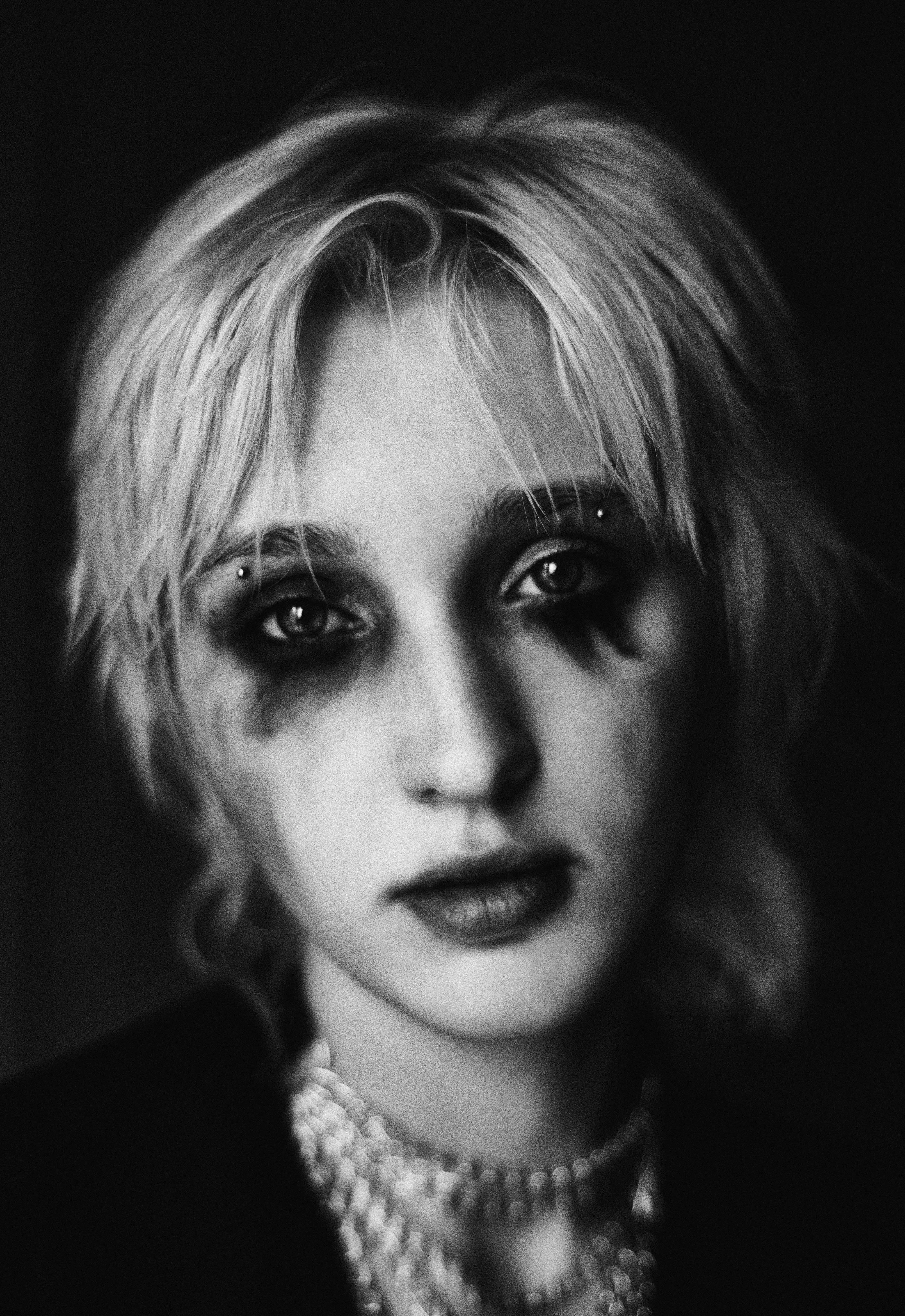 Black and white person with smudged dark eye makeup.