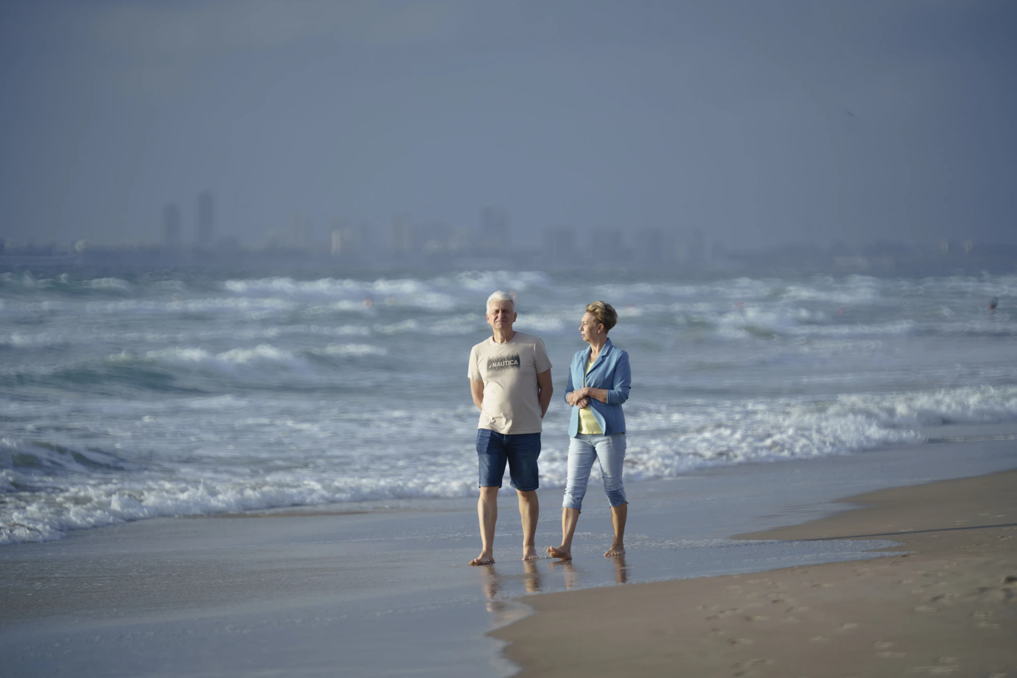 An older couple standing together on a beach