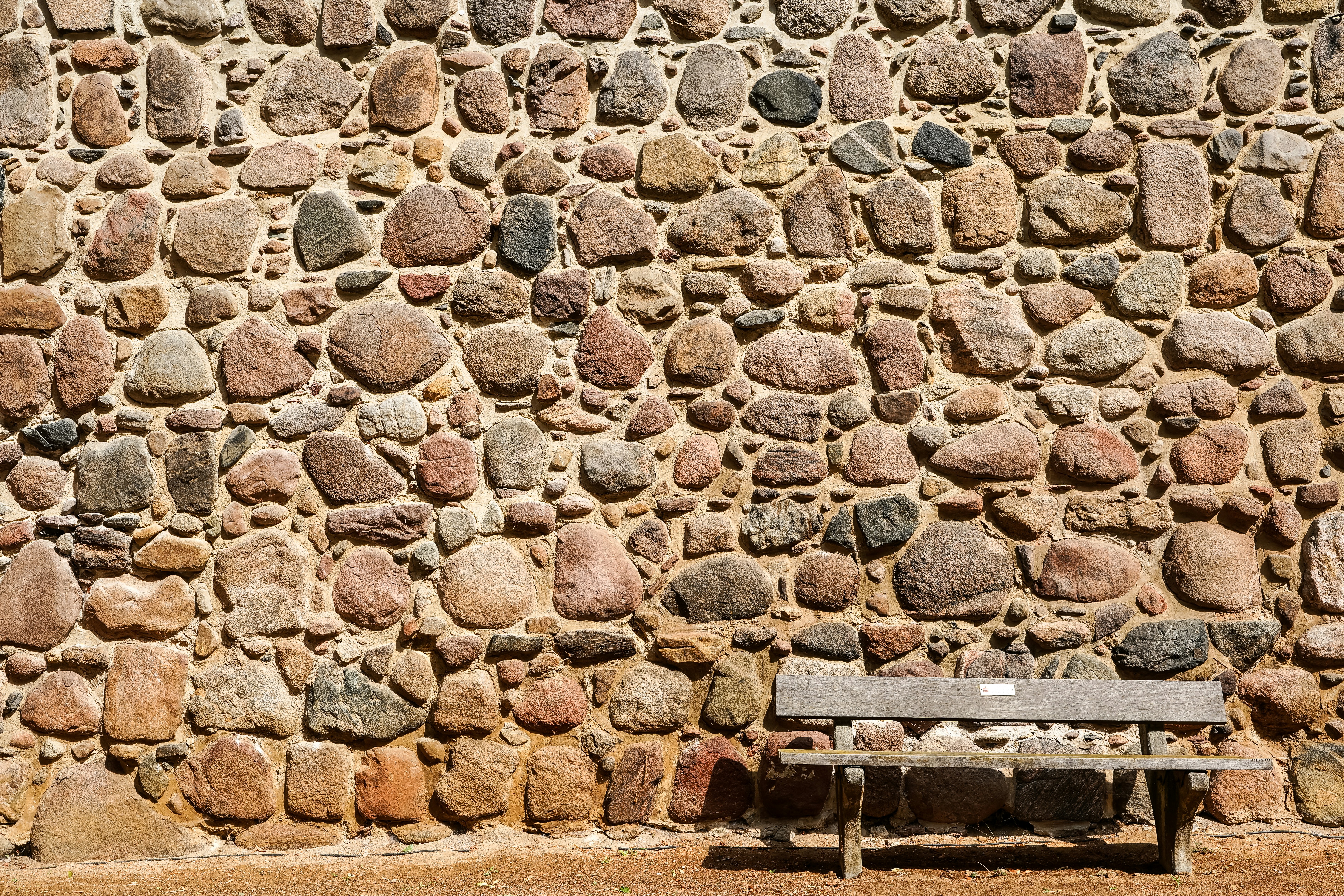 Rustic stone wall with a wooden bench.