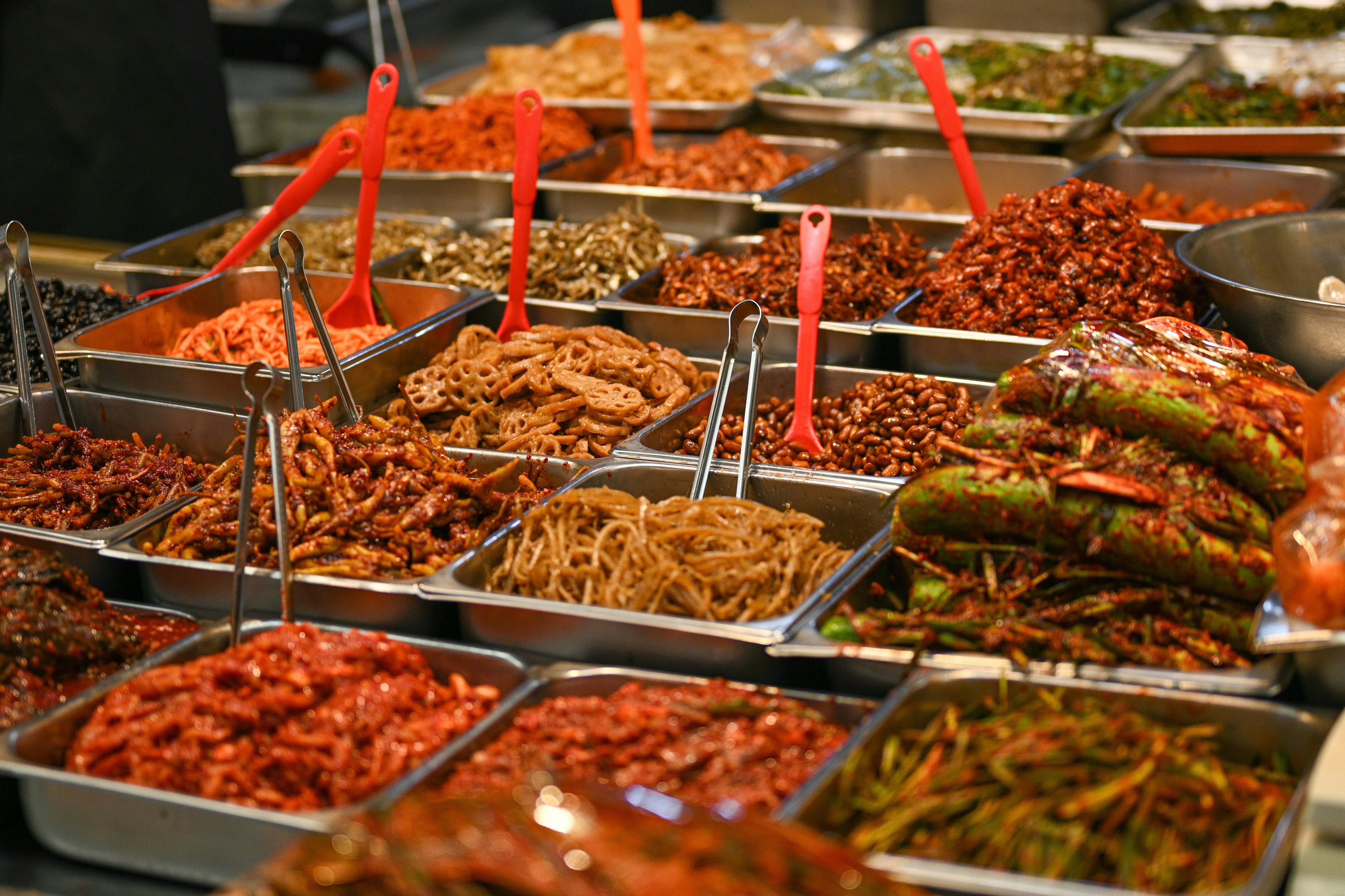 Assorted korean side dishes displayed in metal trays.