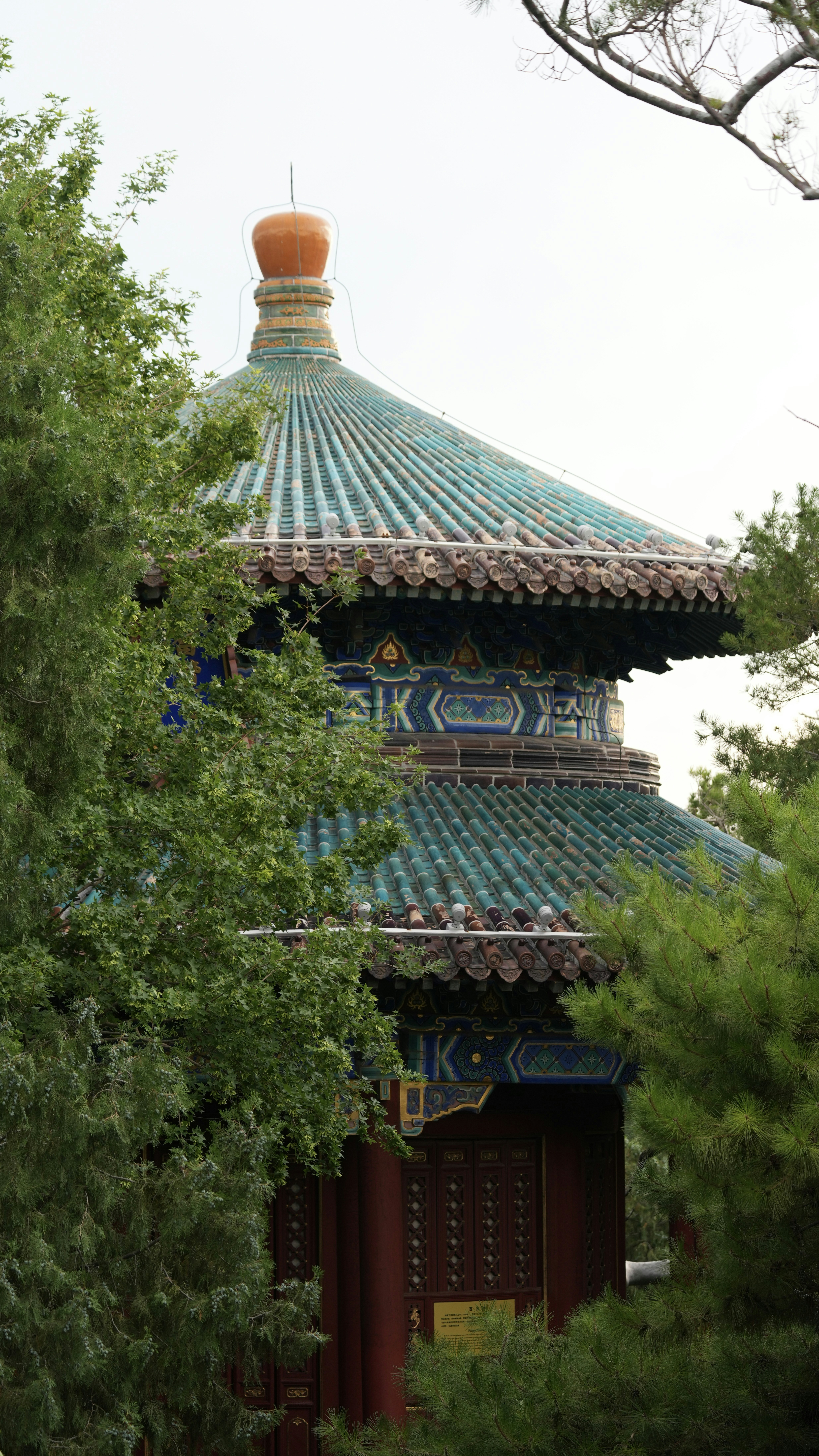 Traditional chinese pagoda with green tiled roof among trees.