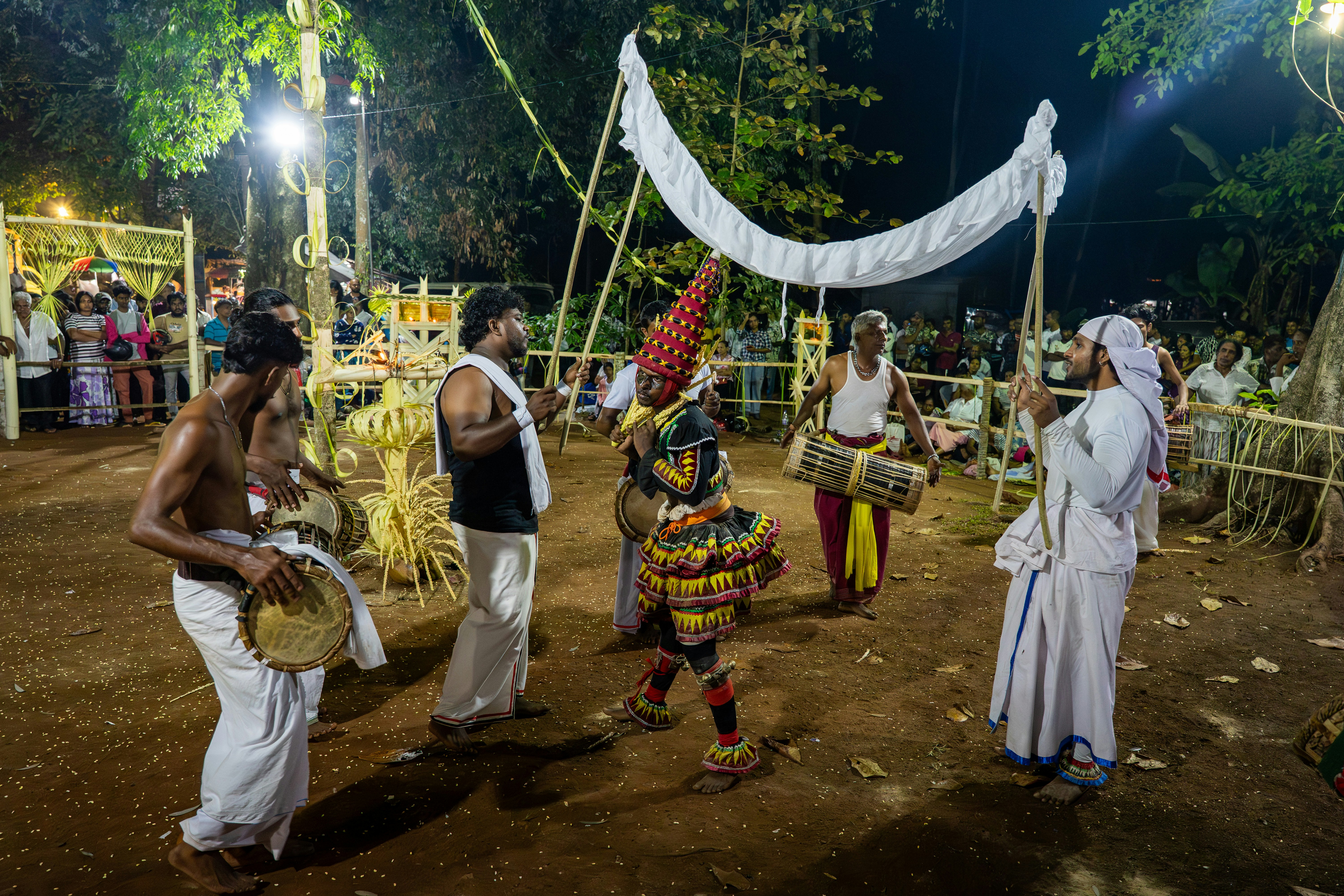 Men perform a vibrant traditional dance with drums at night.