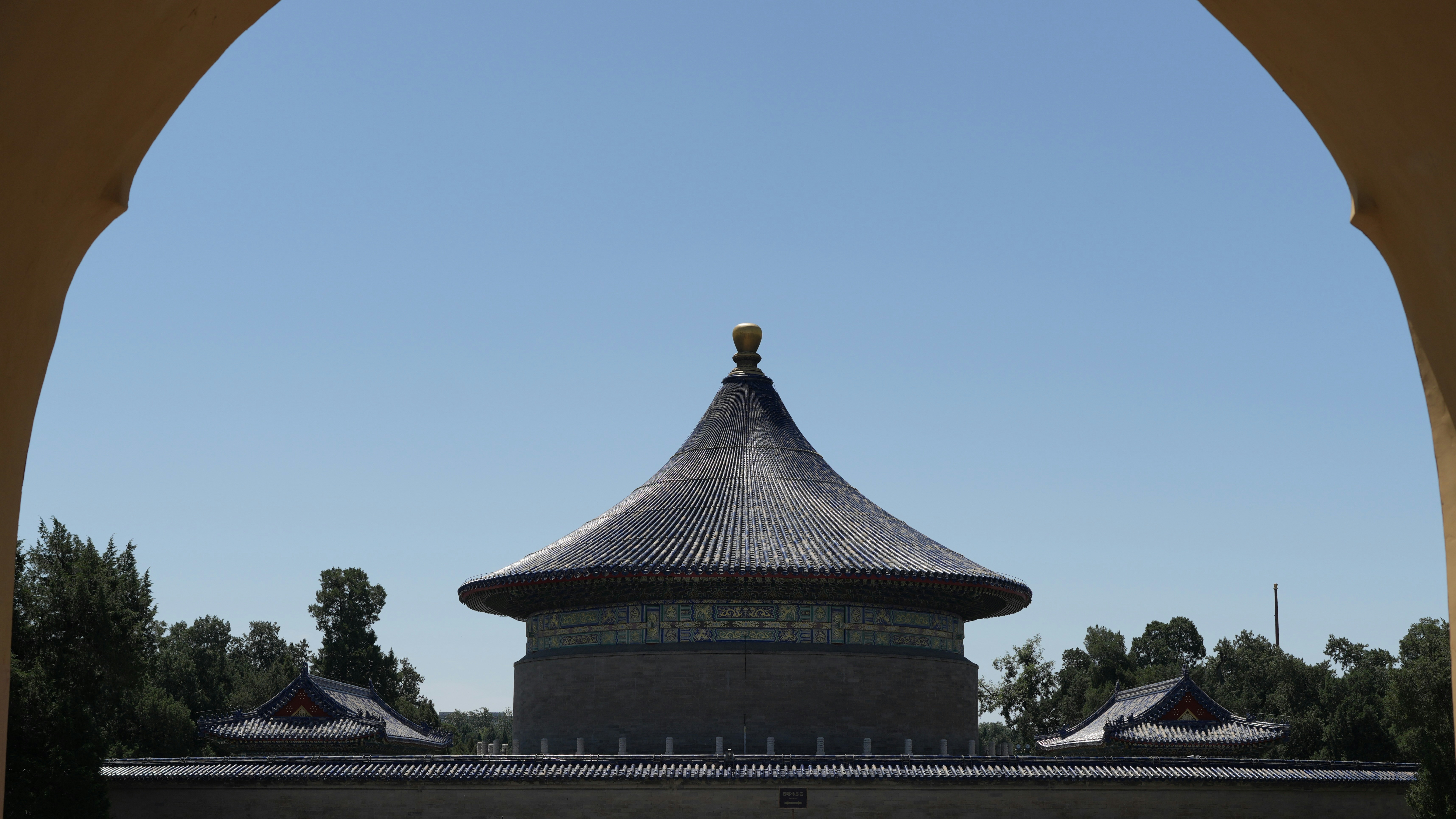 Traditional asian building with conical roof framed by an archway.