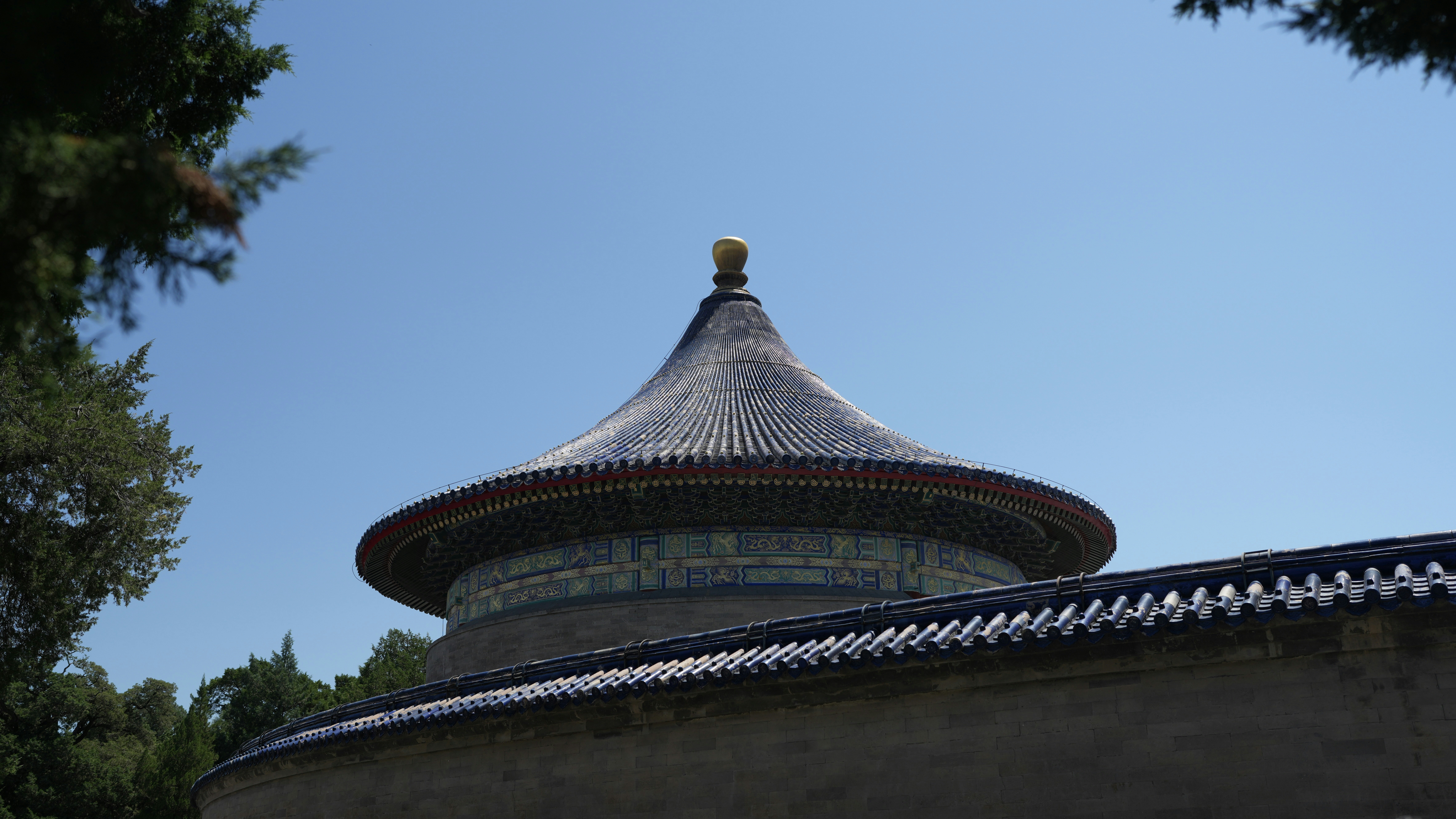 Ancient chinese temple roof with dark tiles against blue sky.