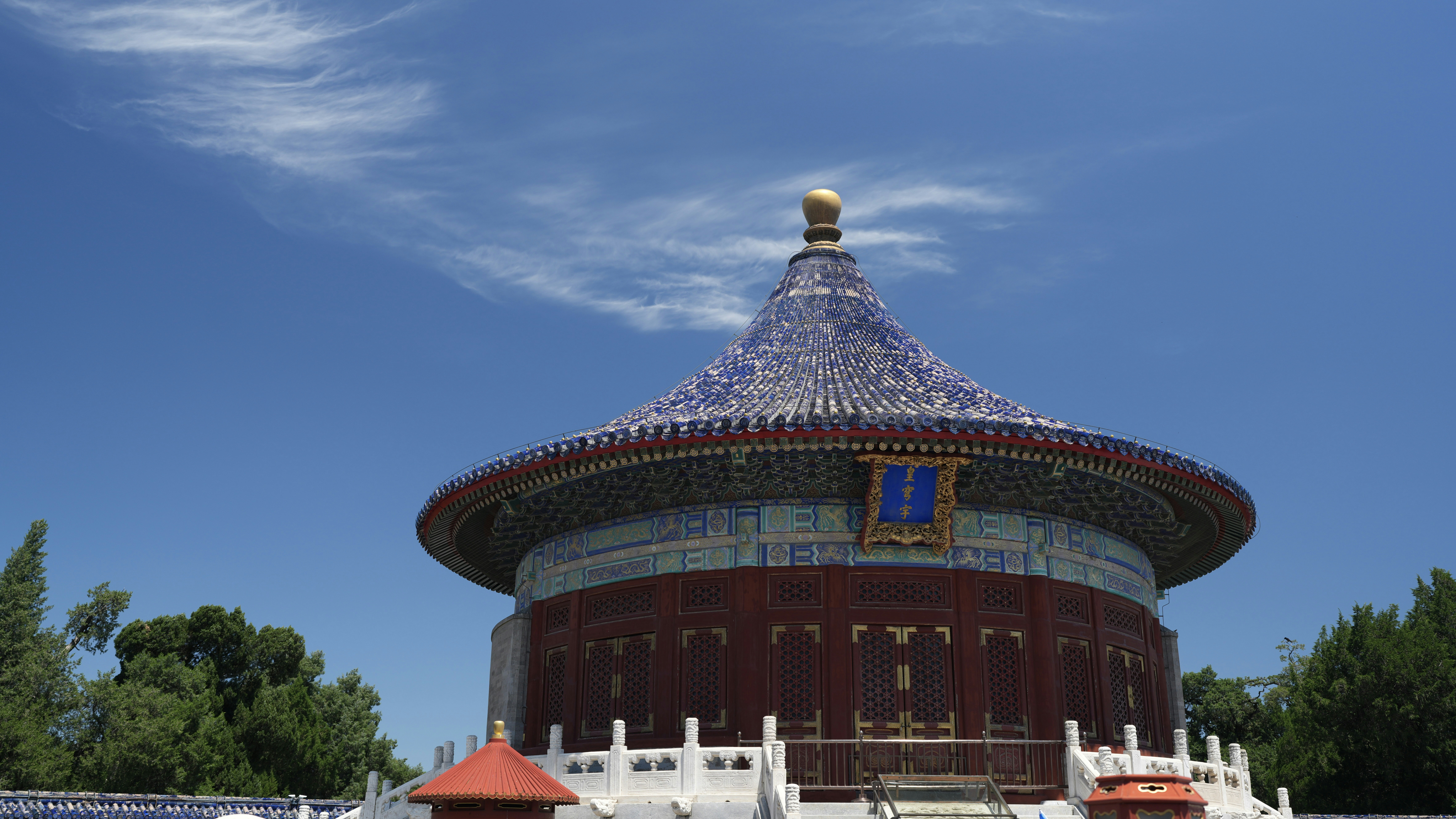 Round temple building with blue roof under a clear sky.