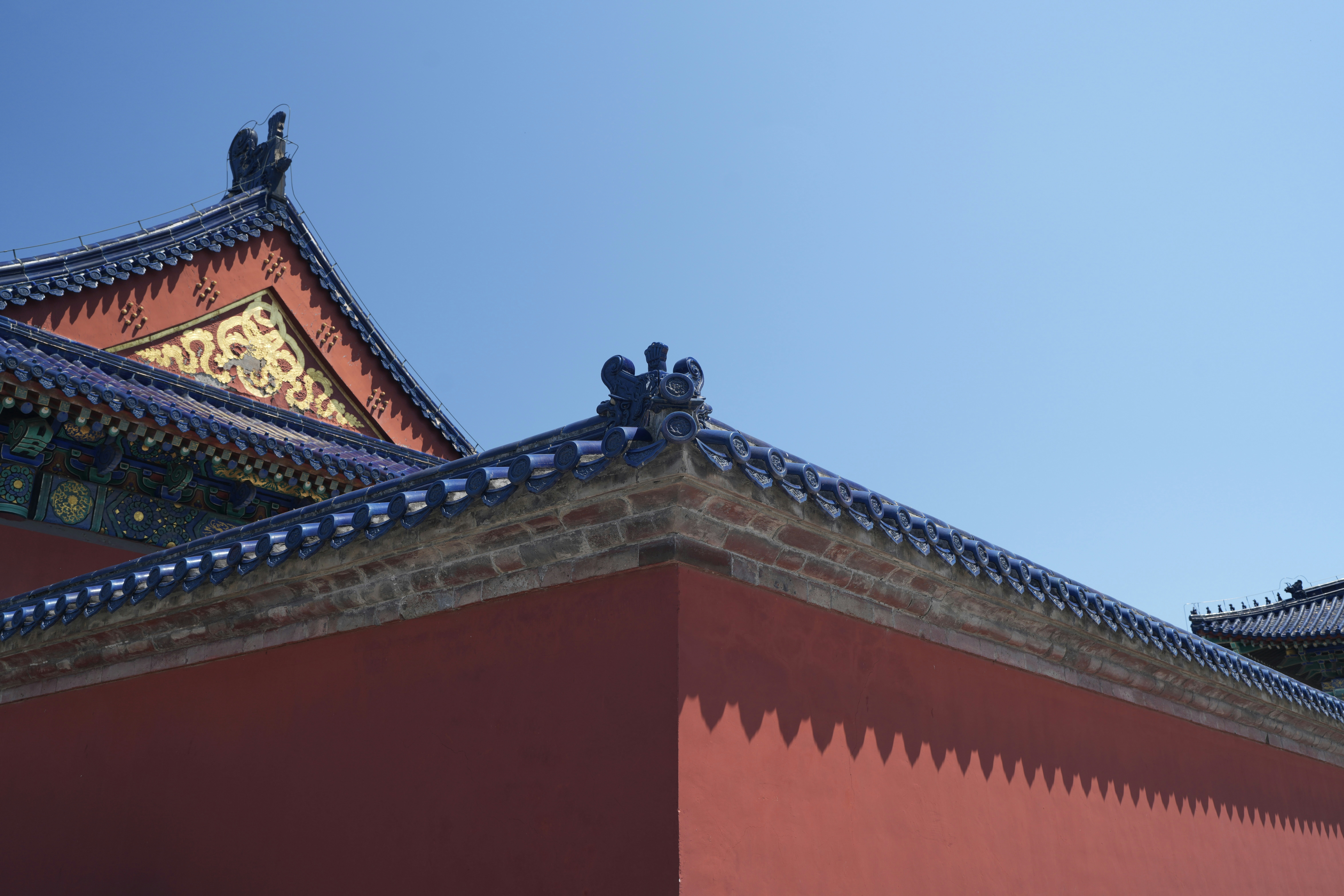 Traditional chinese building with red walls and blue tiled roof.