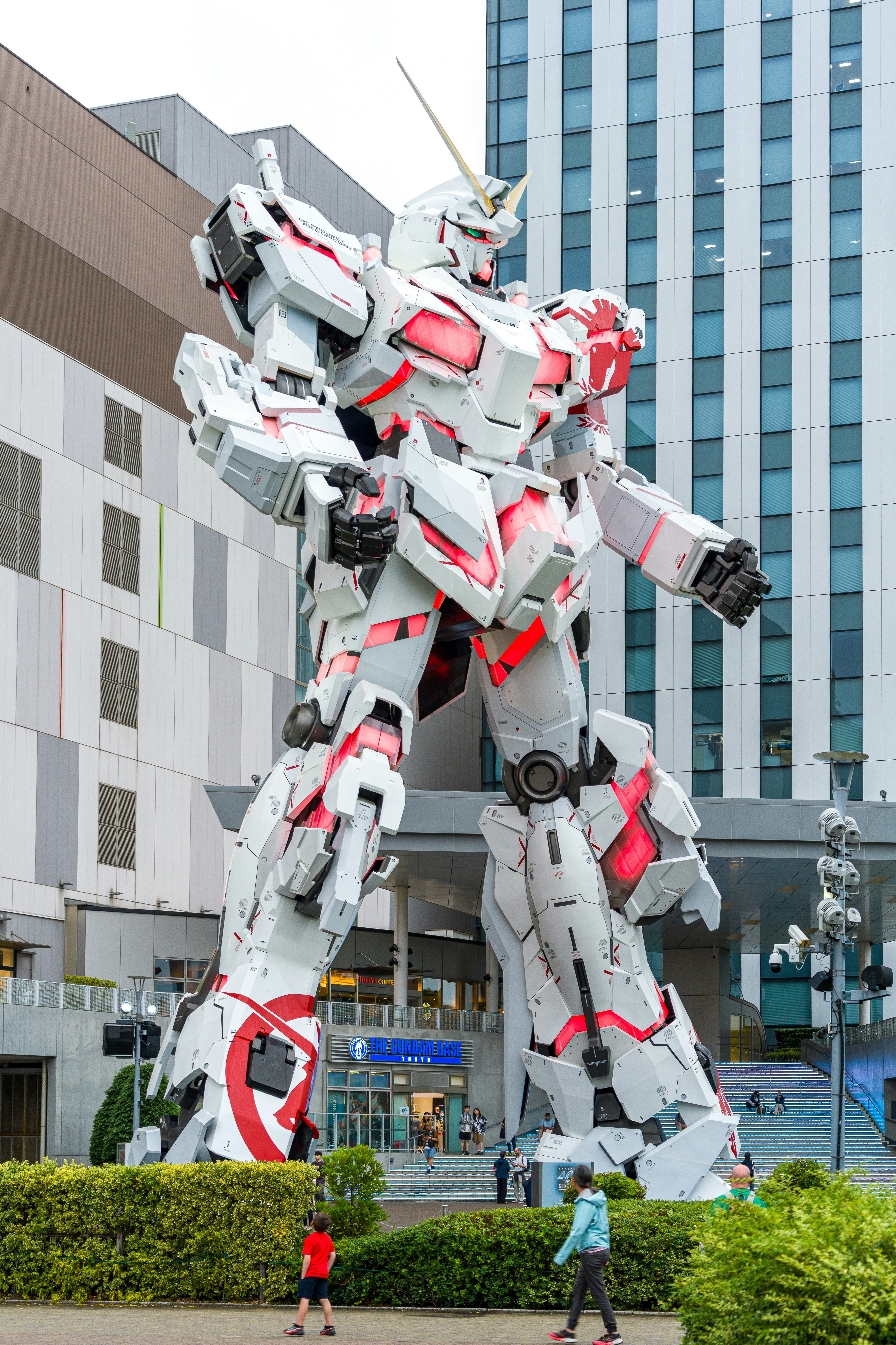 Massive white robot statue with red lights outside a building.