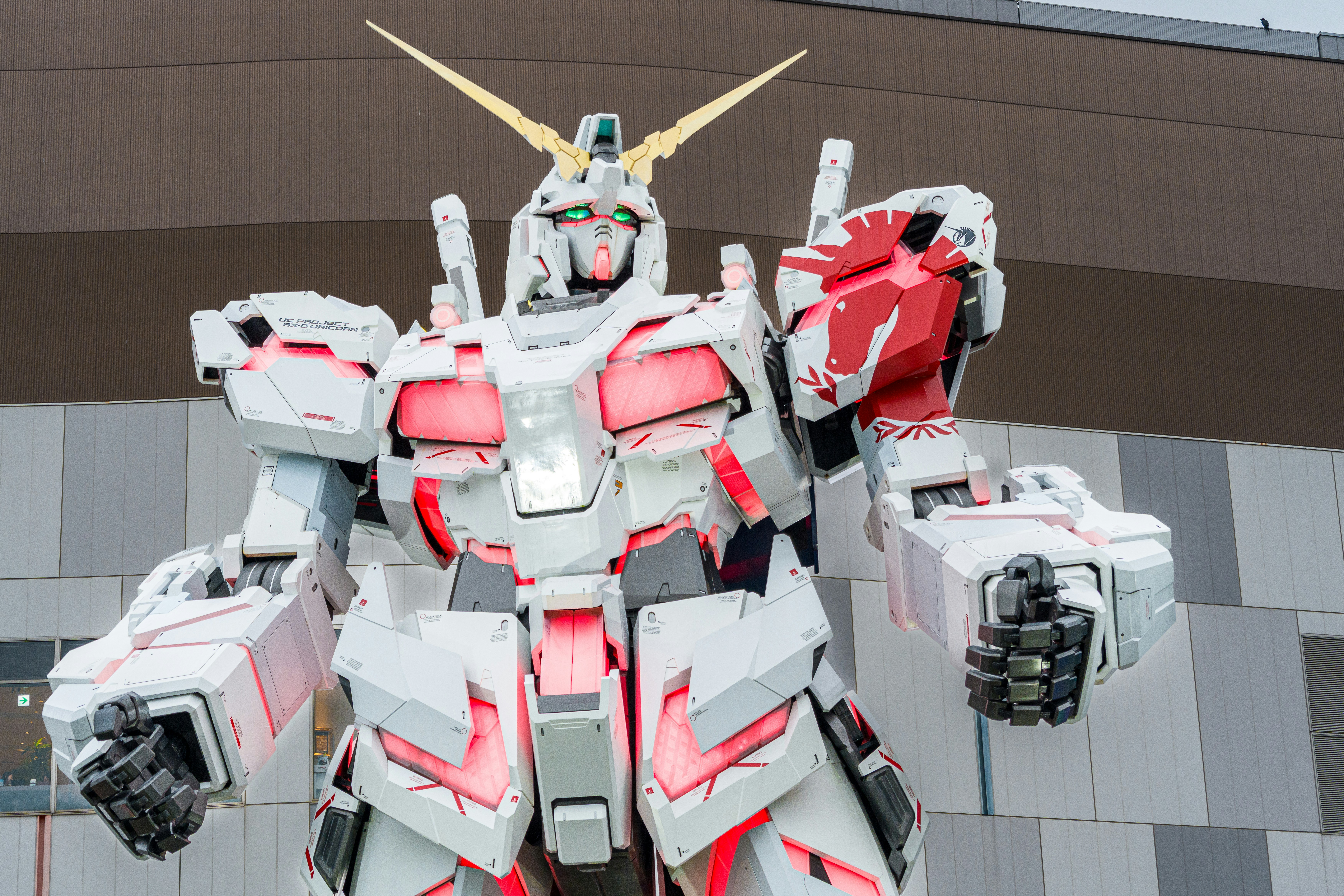 A giant white and red robot statue stands outdoors.