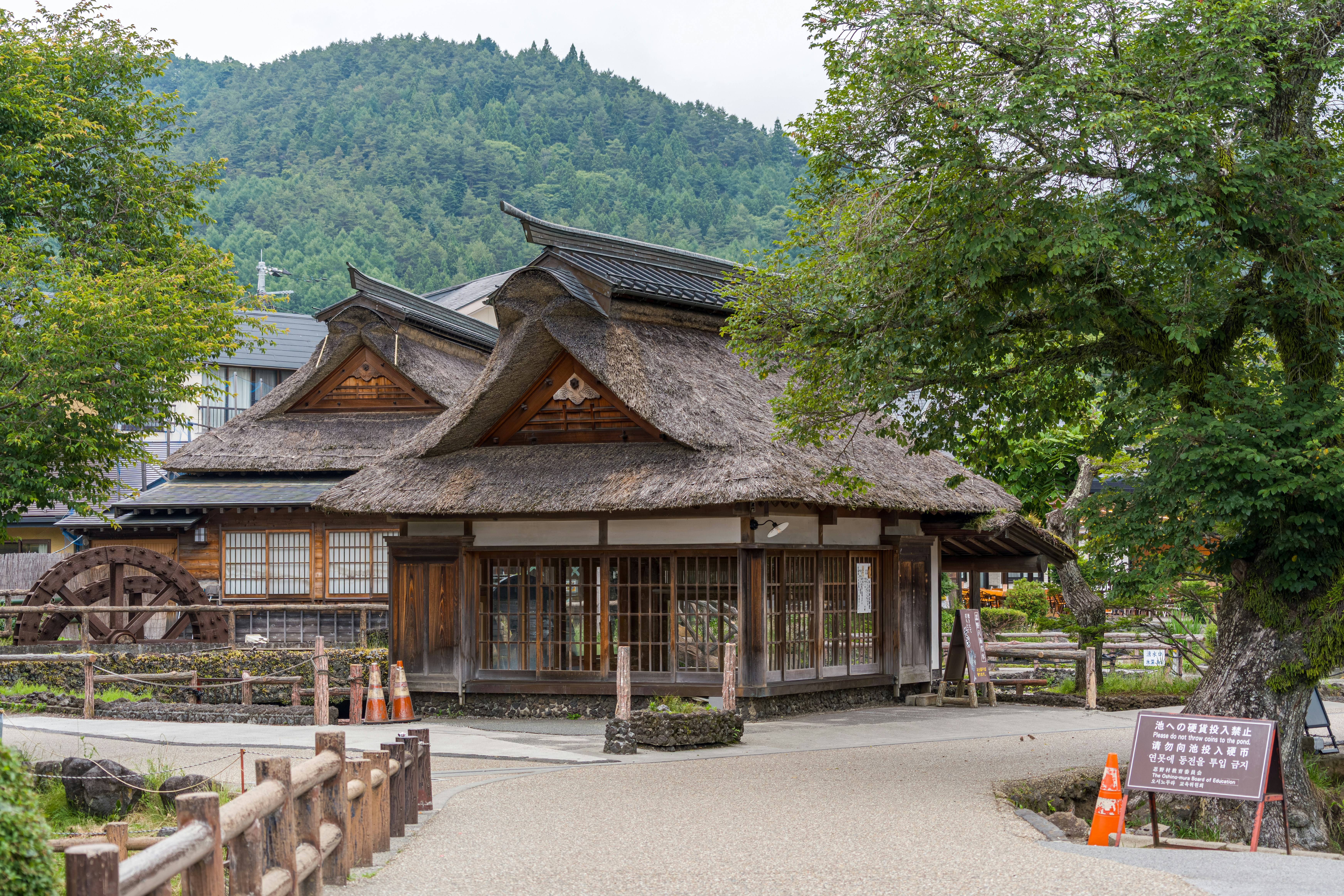 Traditional japanese house with thatched roof and waterwheel.
