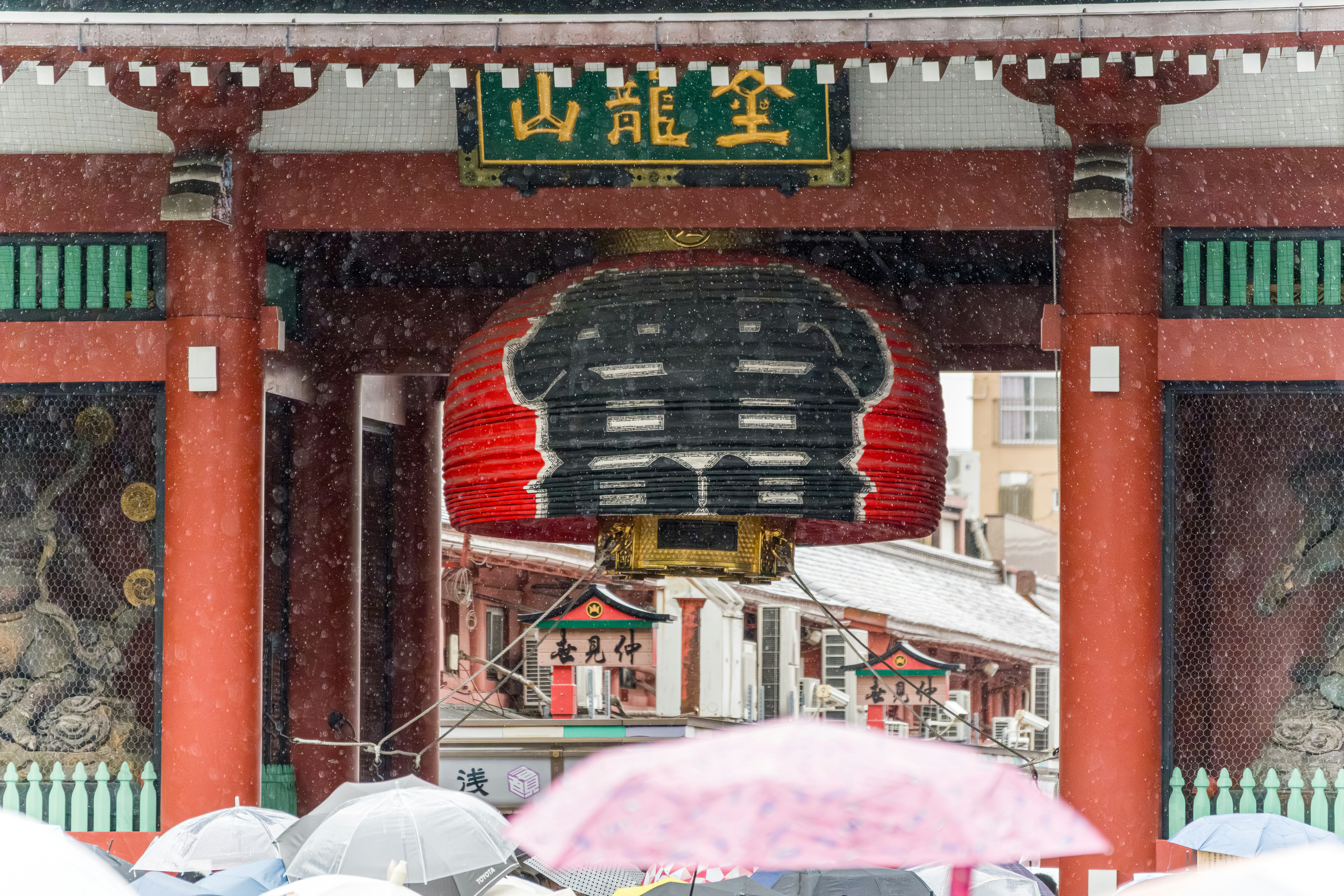 Traditional japanese temple gate and red lantern in the rain.