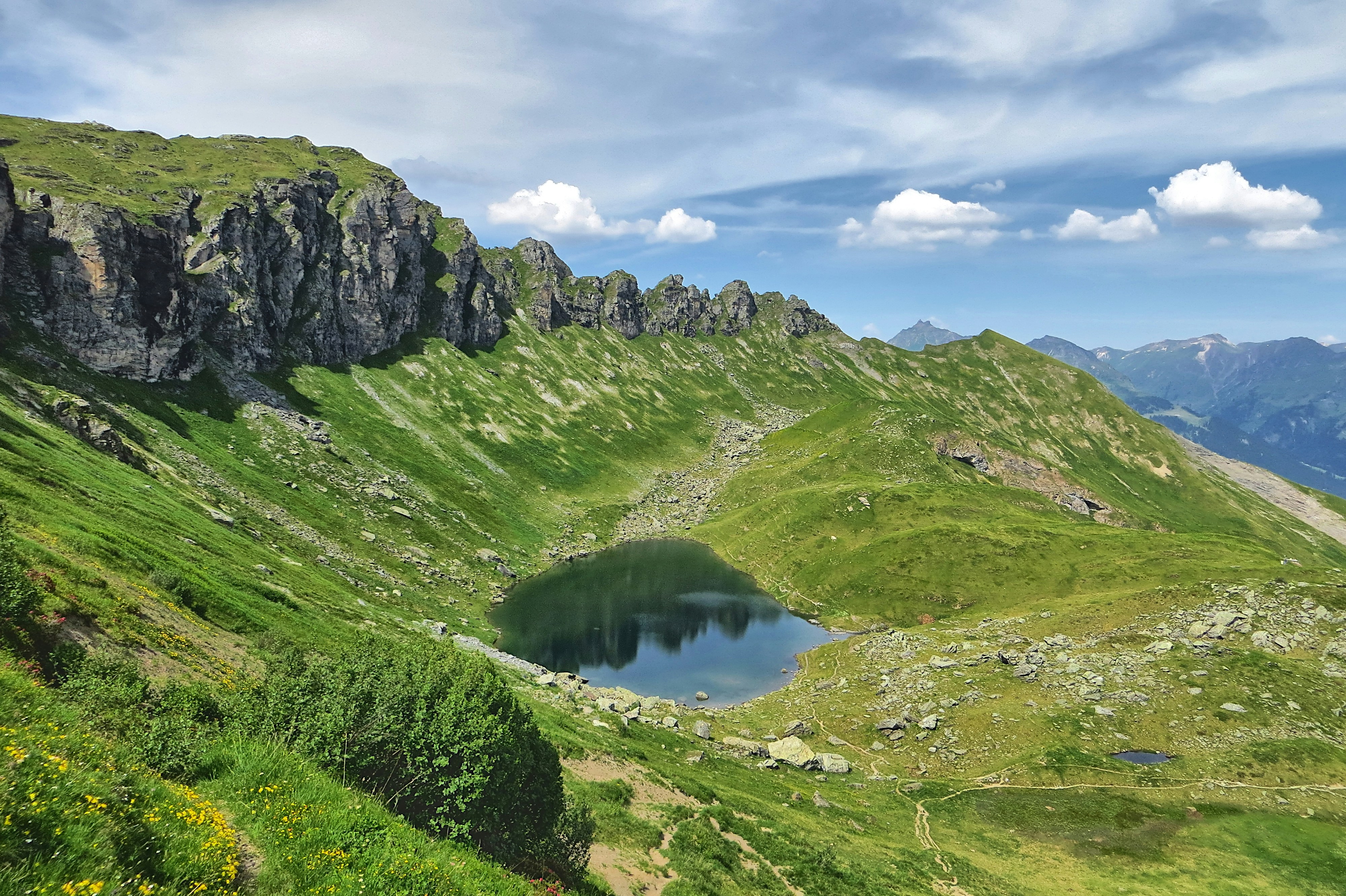 Paisaje montañoso con un lago sereno bajo un cielo nublado.