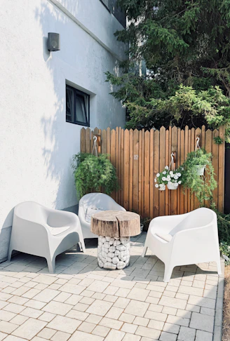 Cozy outdoor patio with white chairs and a rustic table.
