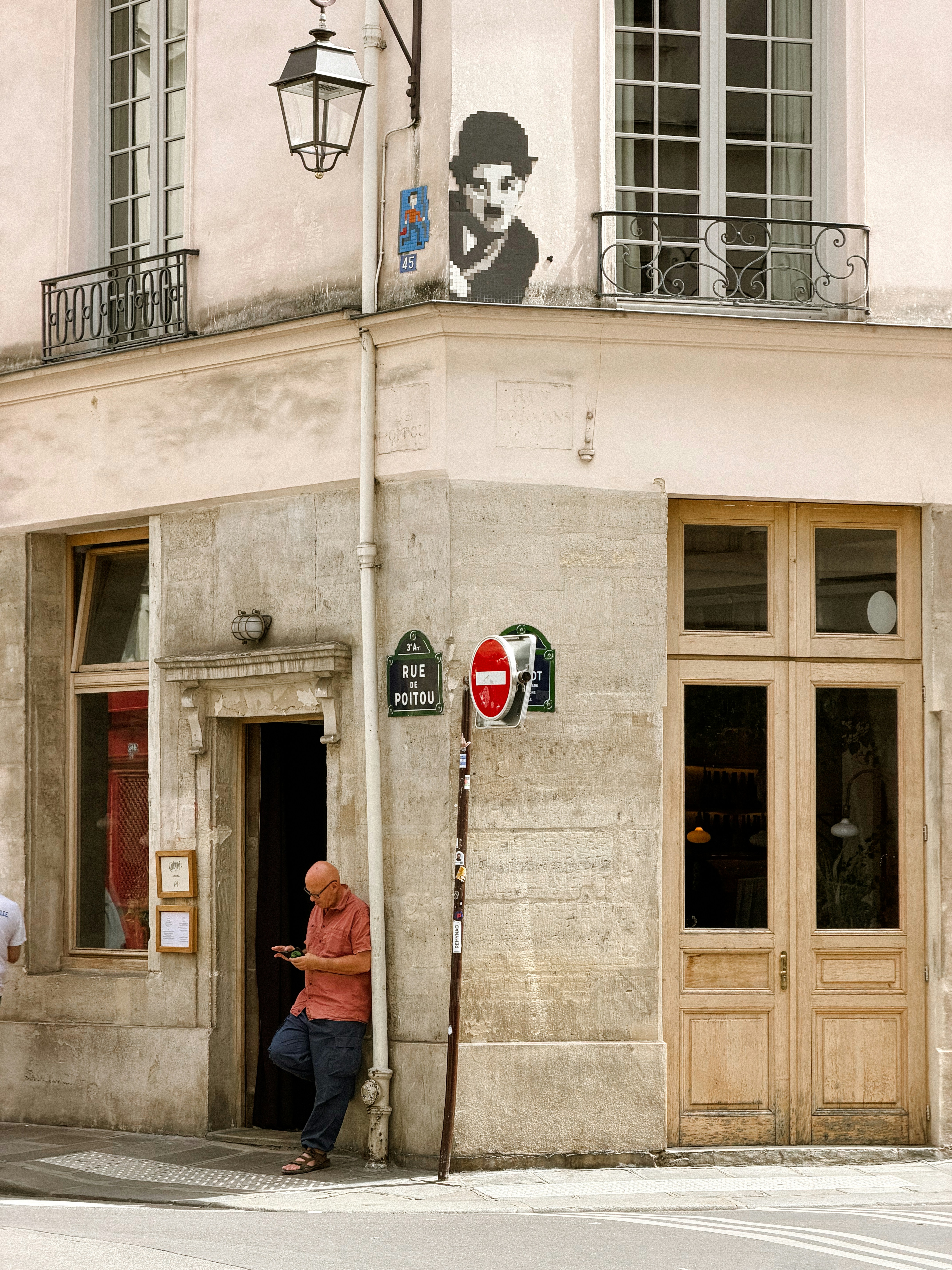 Man leaning on building corner with charlie chaplin stencil art.