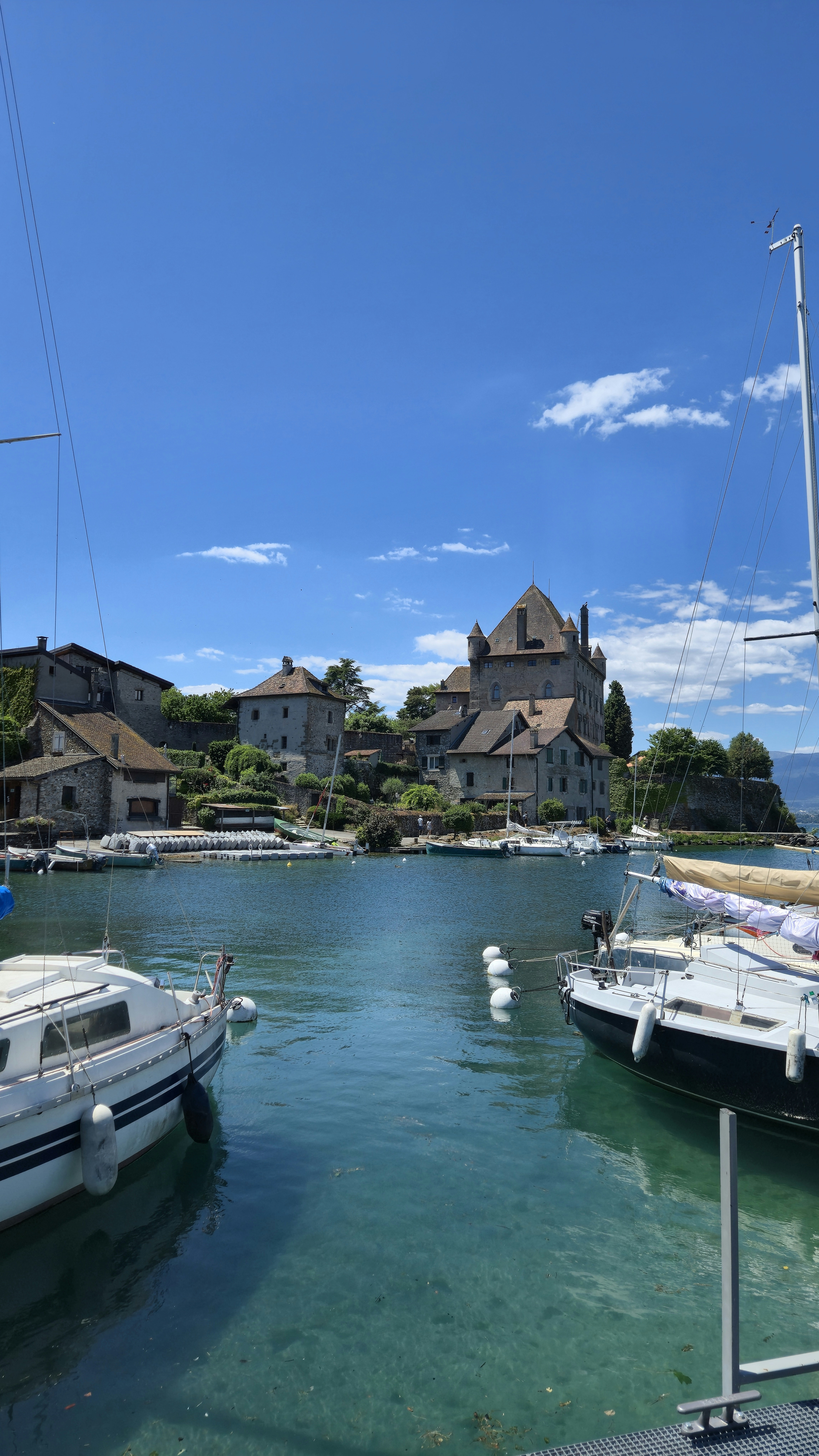 Boats in a clear blue harbor with a historic village.