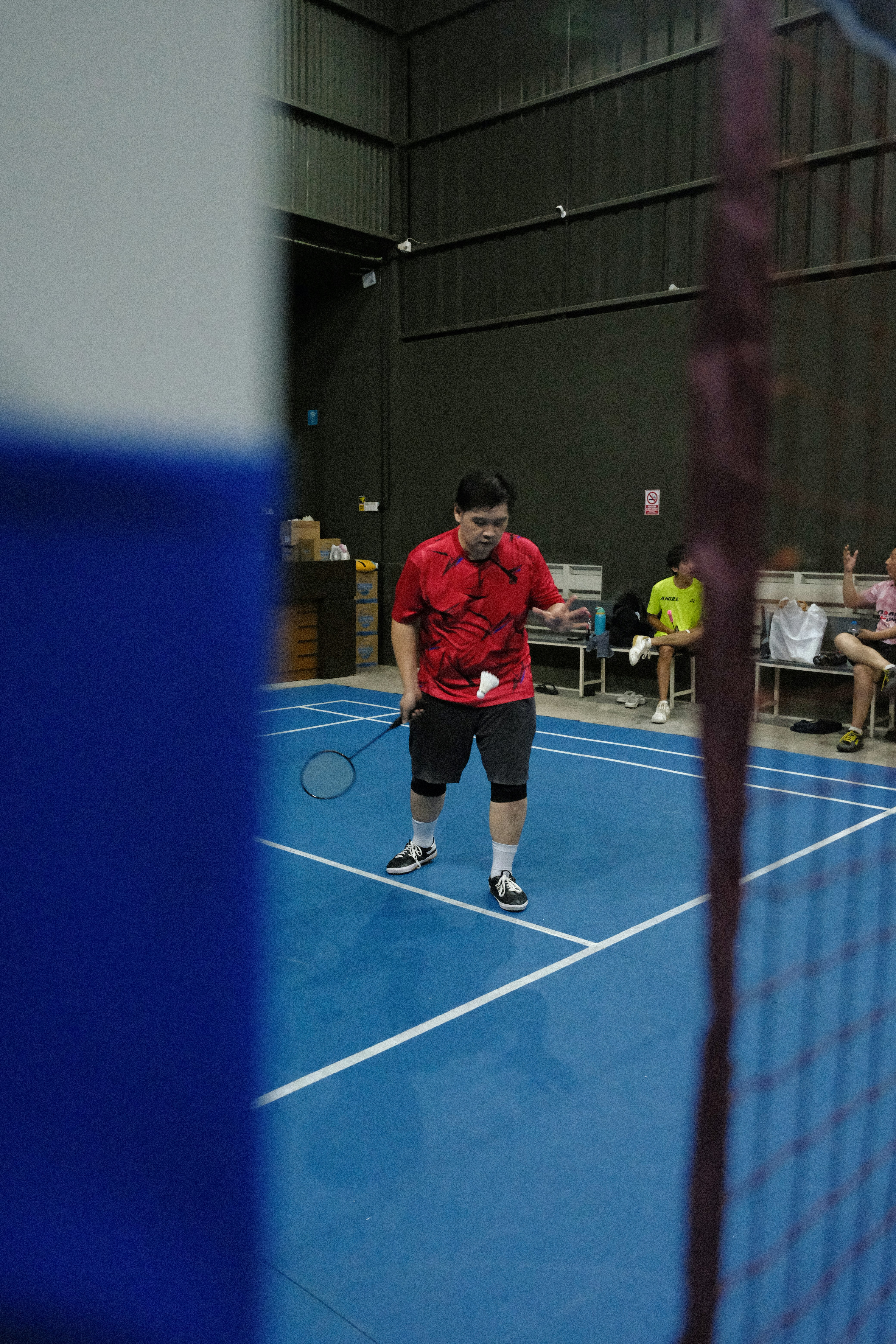 A man plays badminton on a blue court indoors