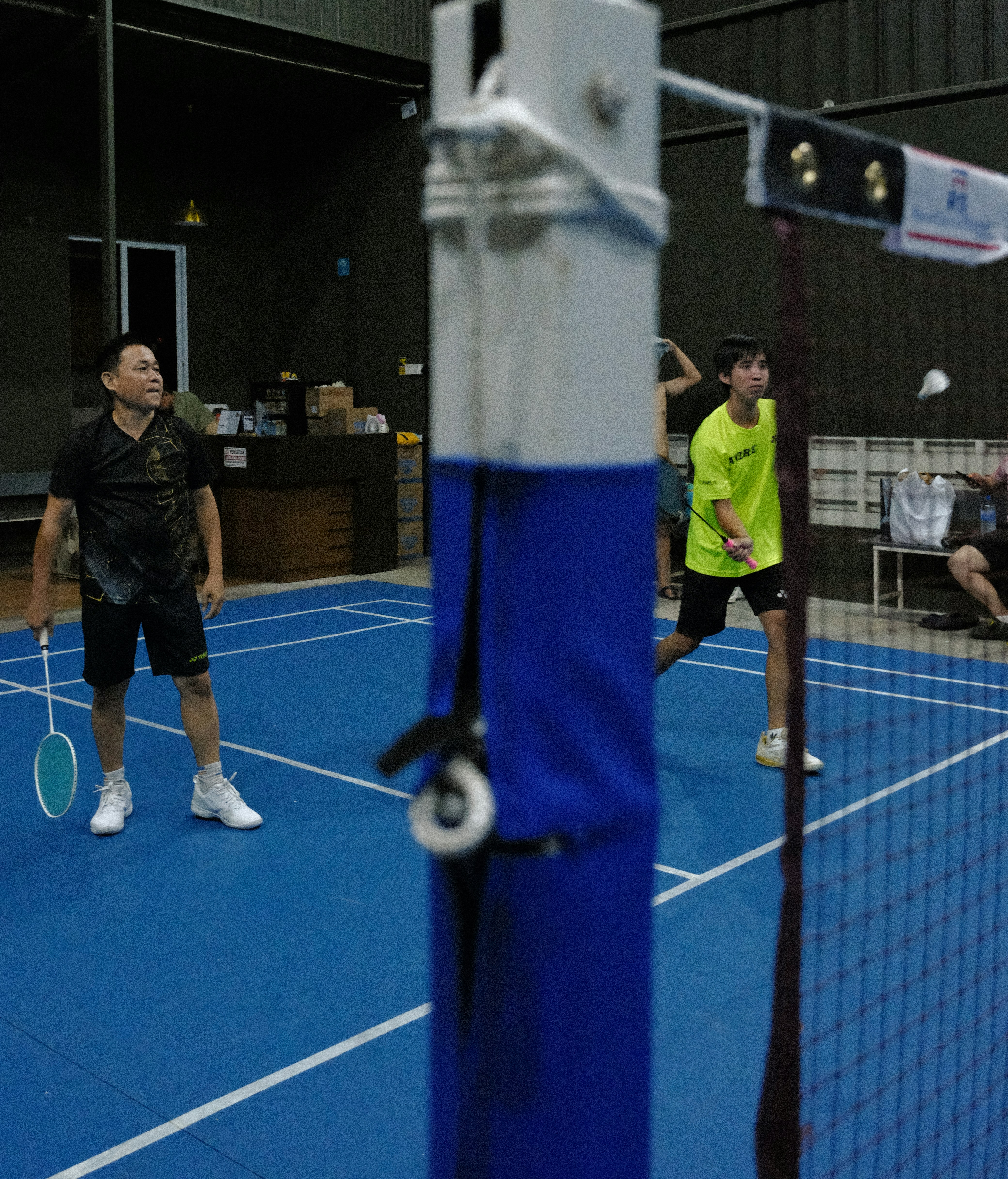 Two men playing badminton on a blue court