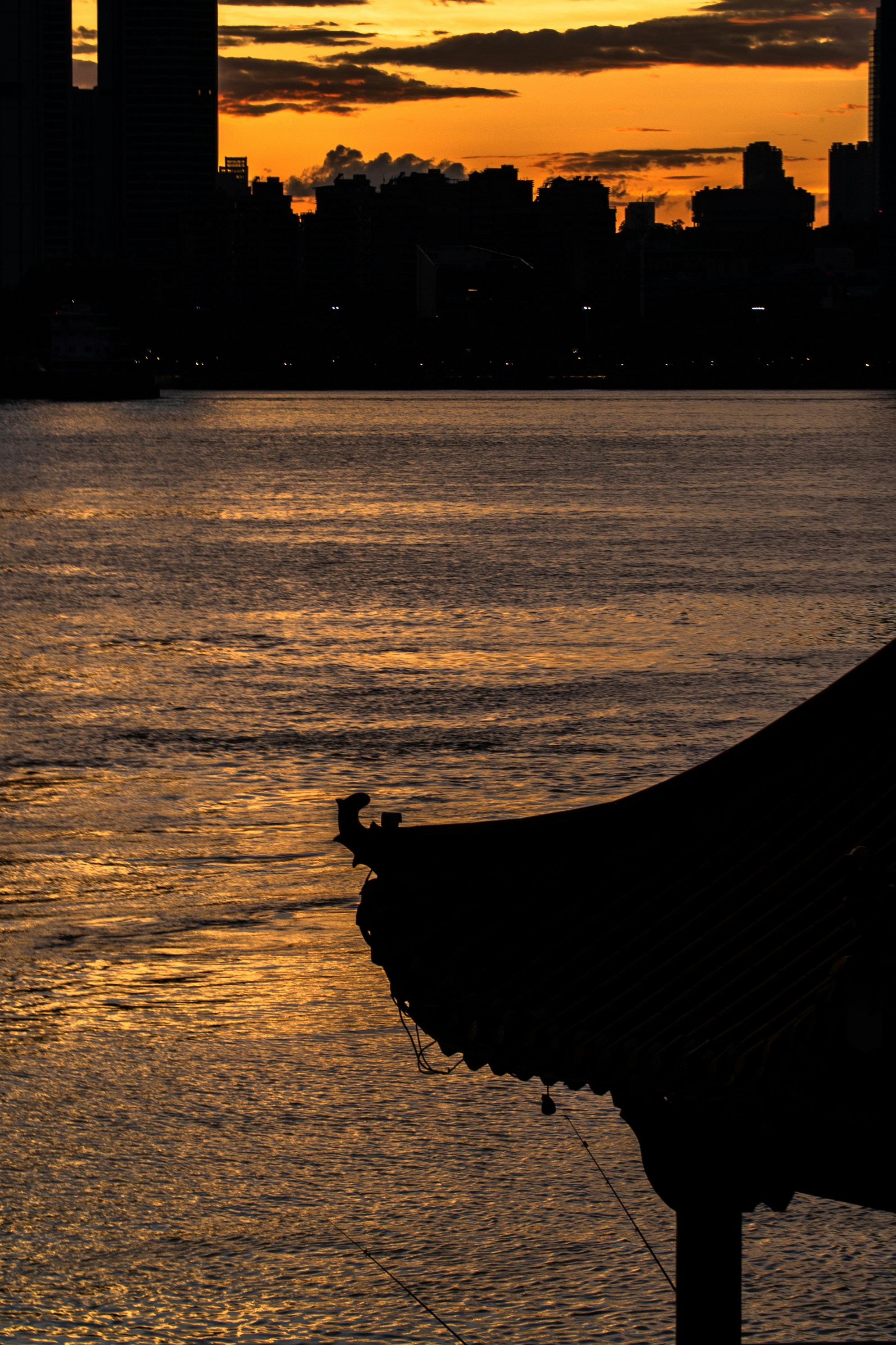 Golden sunset over water, silhouetting city and traditional roof