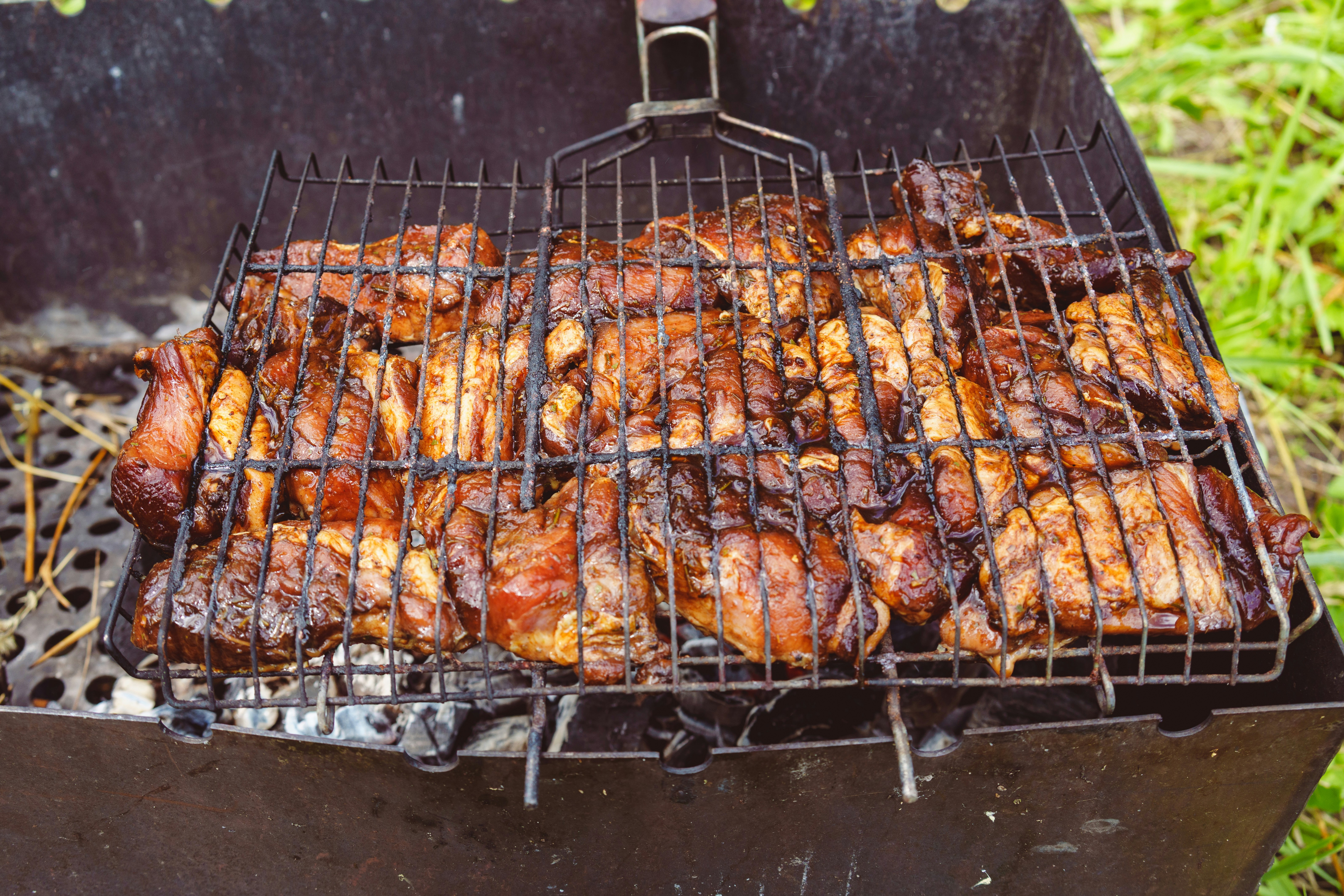Hähnchenstücke, die auf einem Grill im Freien gekocht werden.