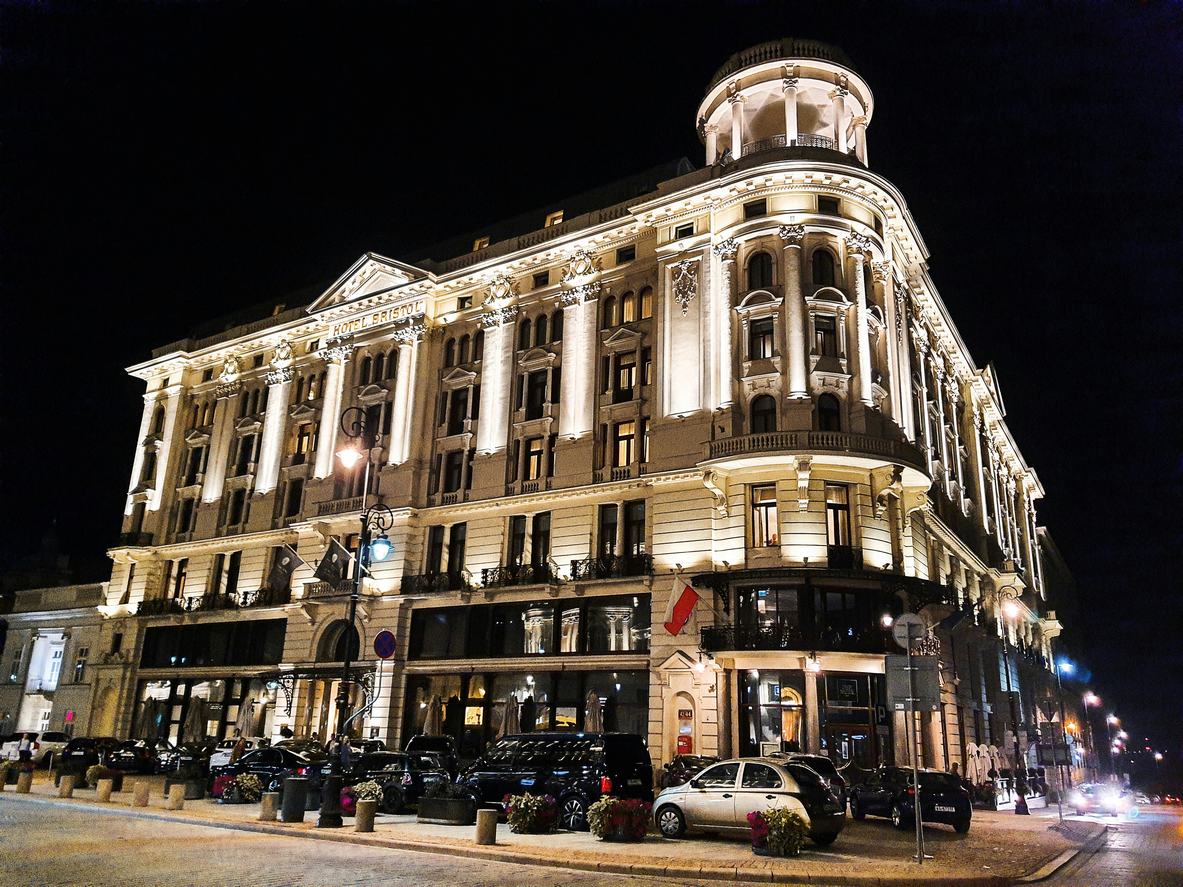 Elegant illuminated building at night with street and parked ca…
