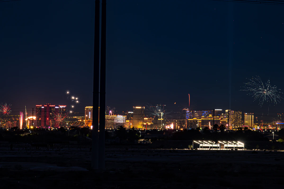 Scattered fireworks going off across a distant city skyline at night