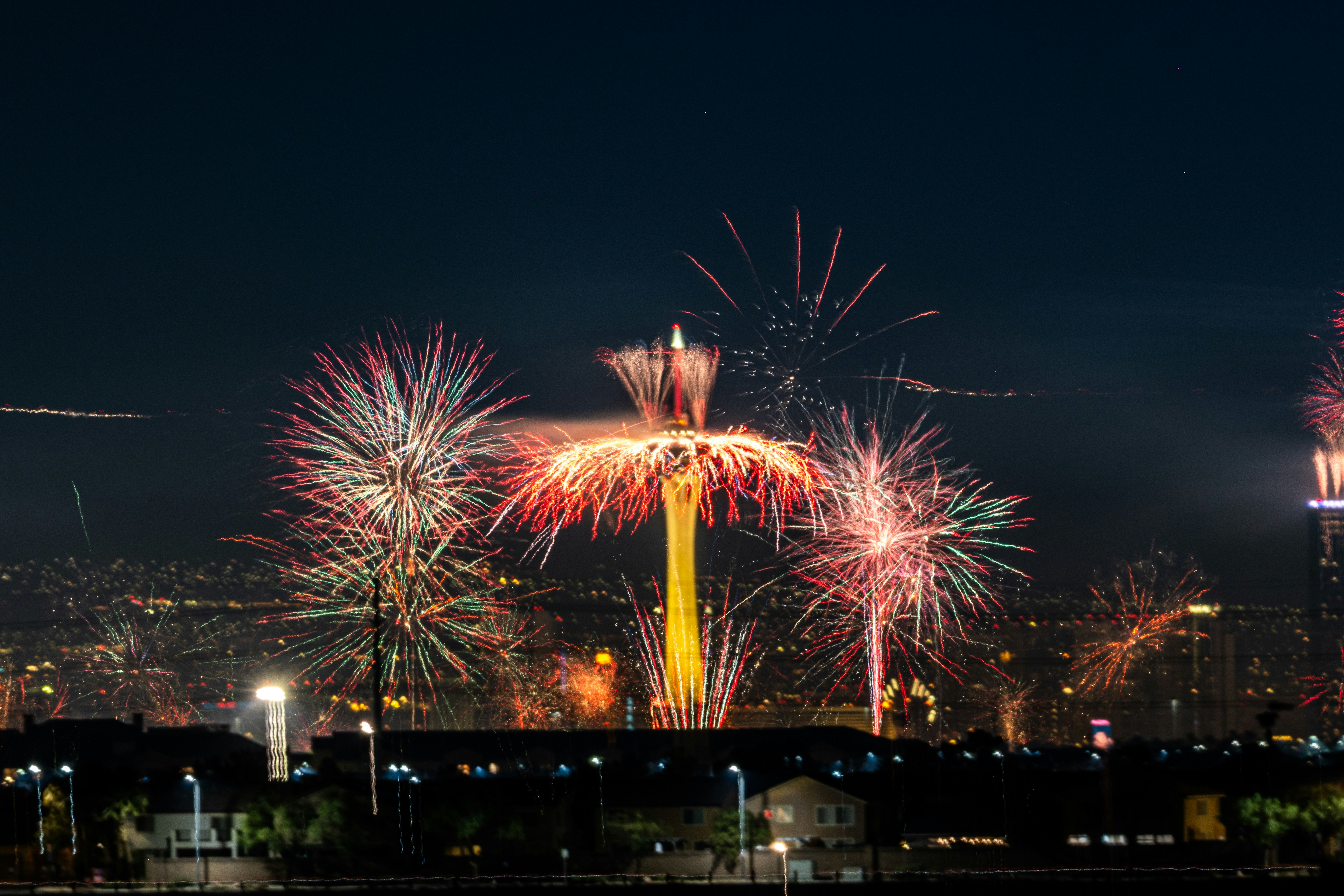 Des feux d’artifice colorés illuminent la silhouette et la tour d’une ville la nuit.
