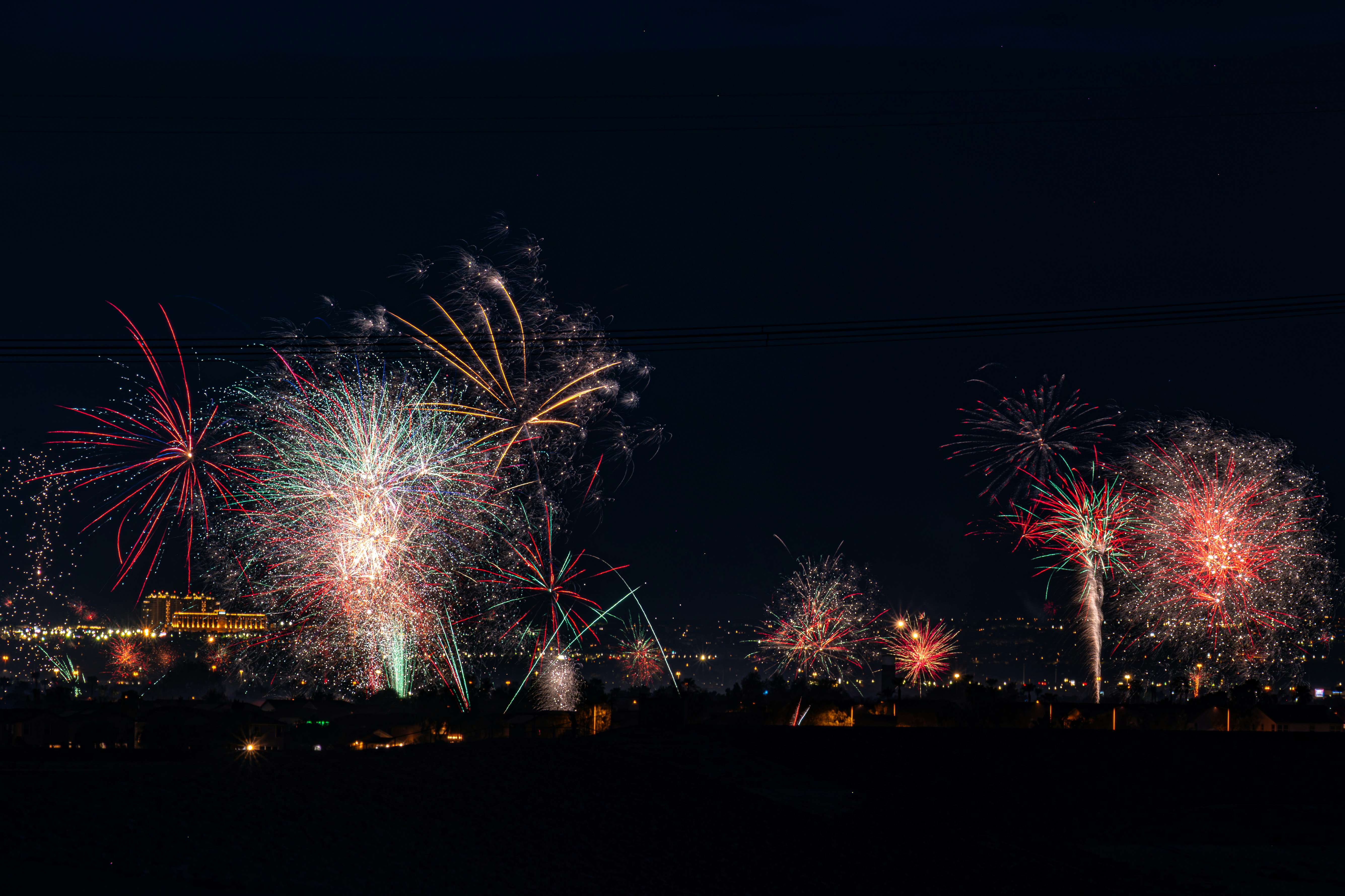 Des feux d’artifice colorés éclatent au-dessus de la ligne d’horizon d’une ville la nuit.