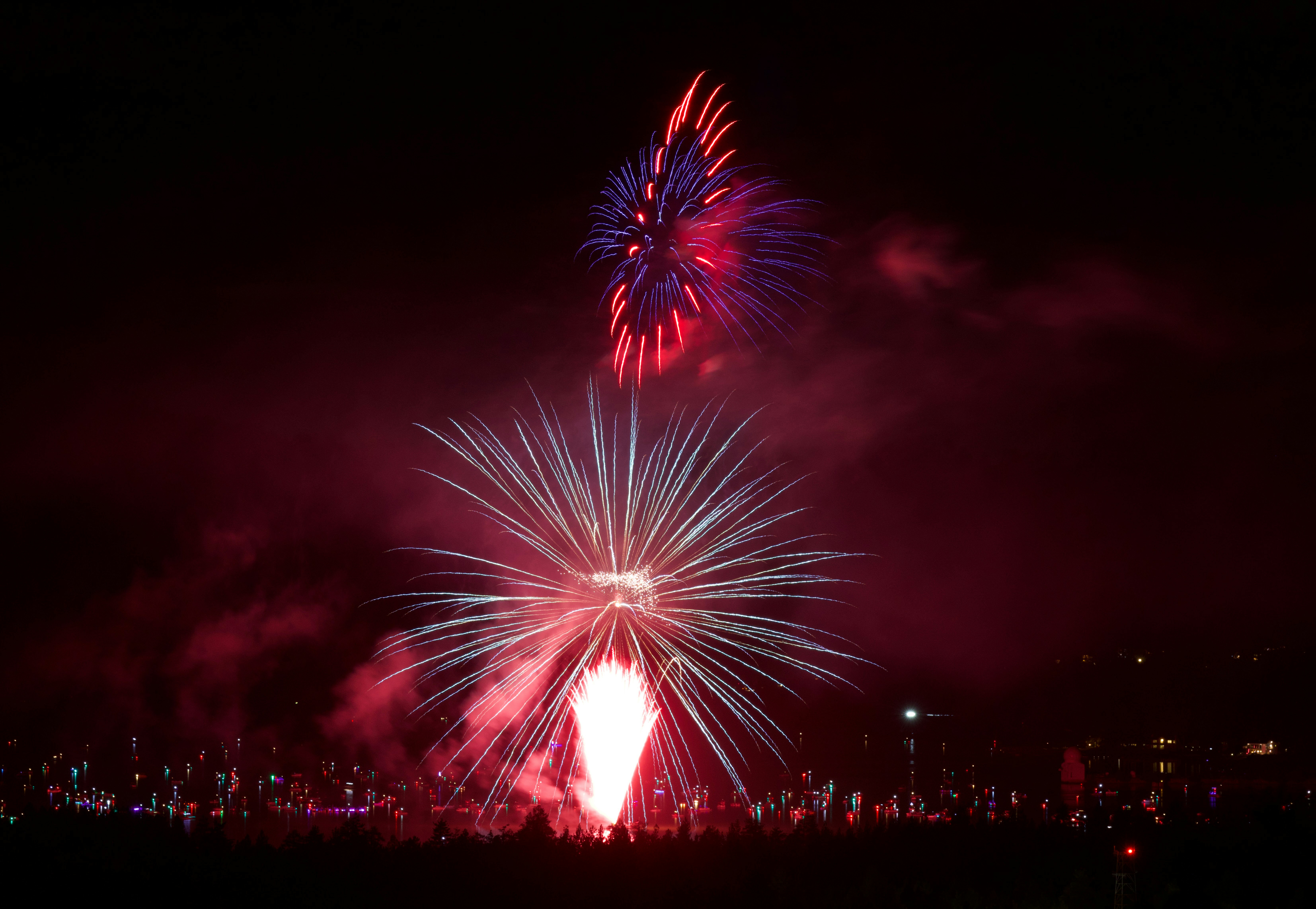 Fuochi d'artificio vivaci illuminano il cielo notturno sopra luci lontane.