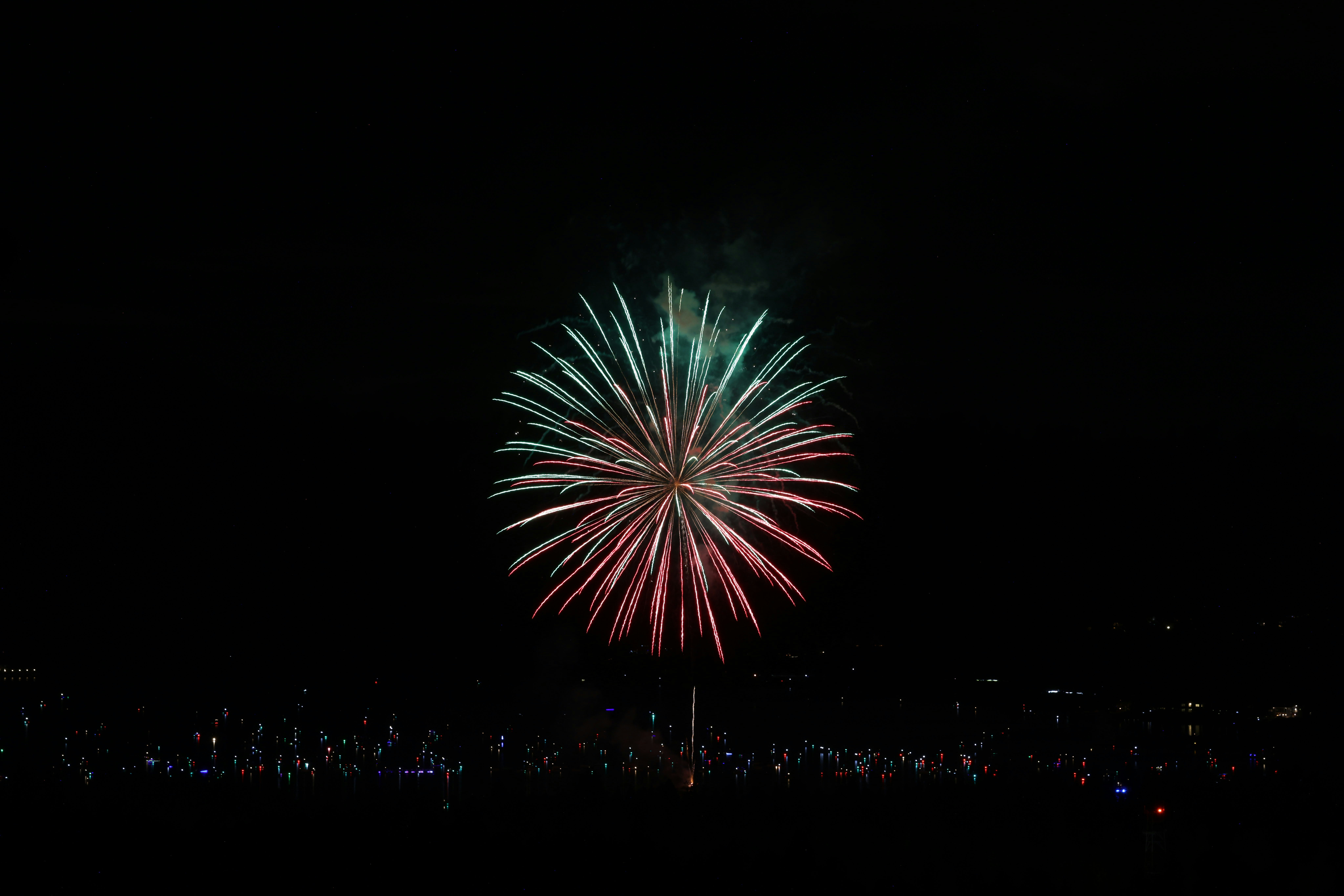 Un singolo fuoco d'artificio vibrante esplode sopra luci lontane di notte.