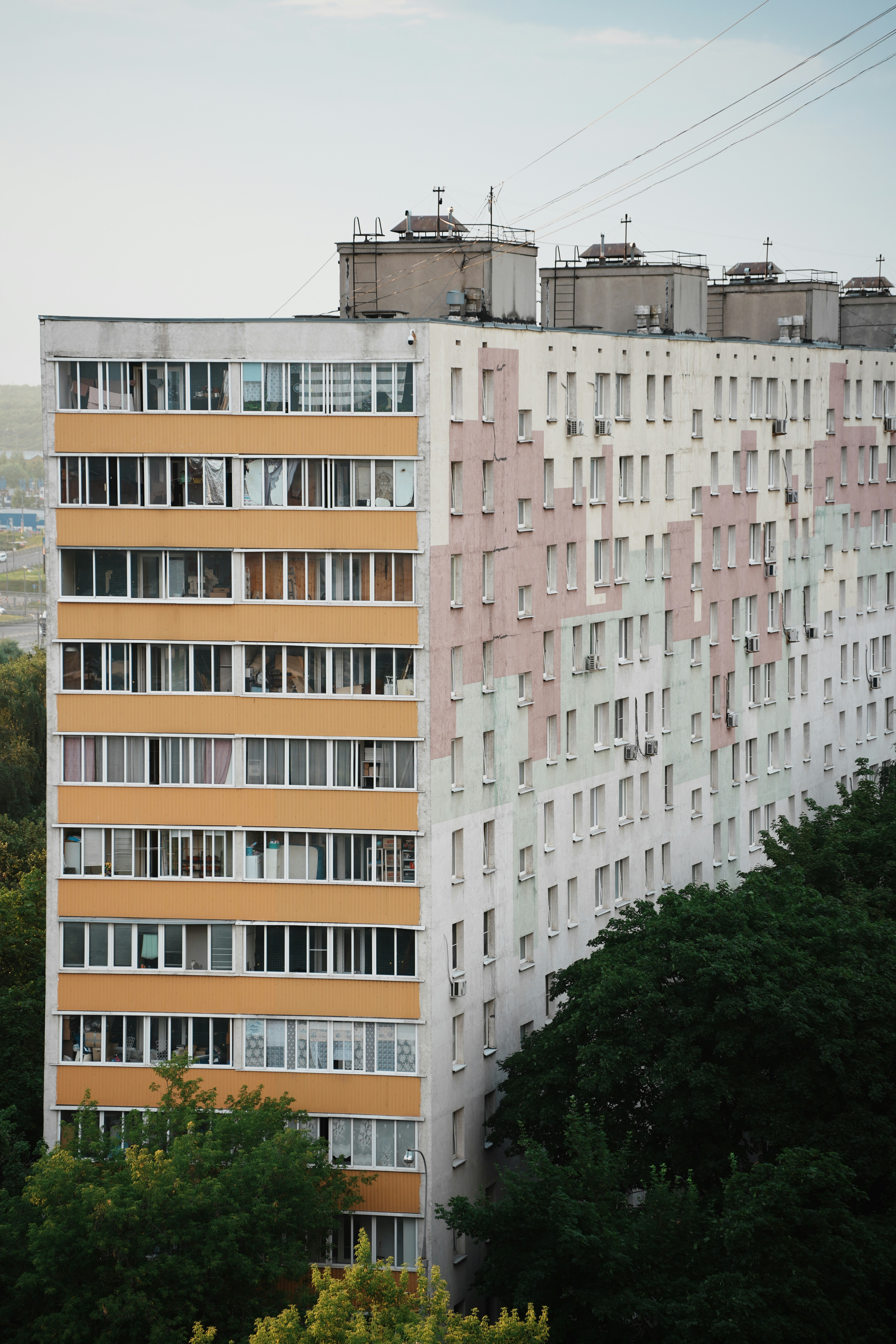 Ein hohes Wohnhaus mit bunten Paneelen und umliegenden Bäumen.