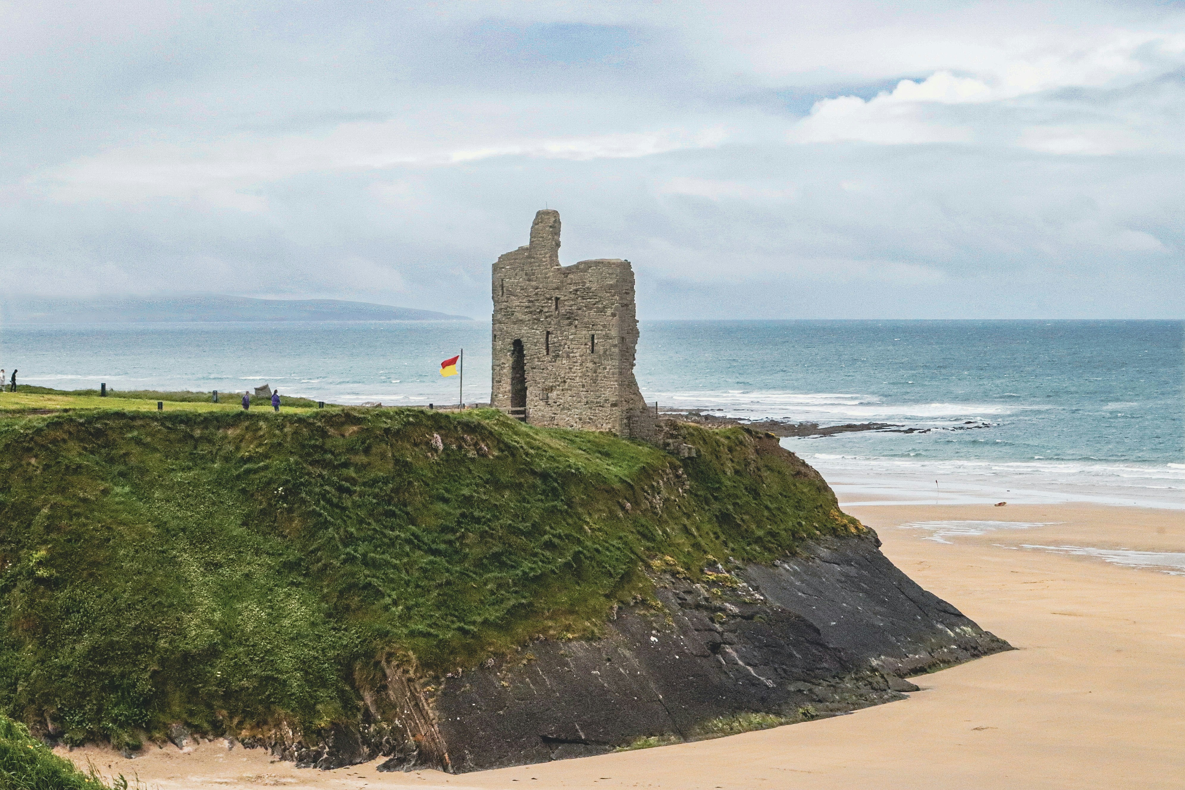Ancient stone ruin on a cliff overlooking a beach.