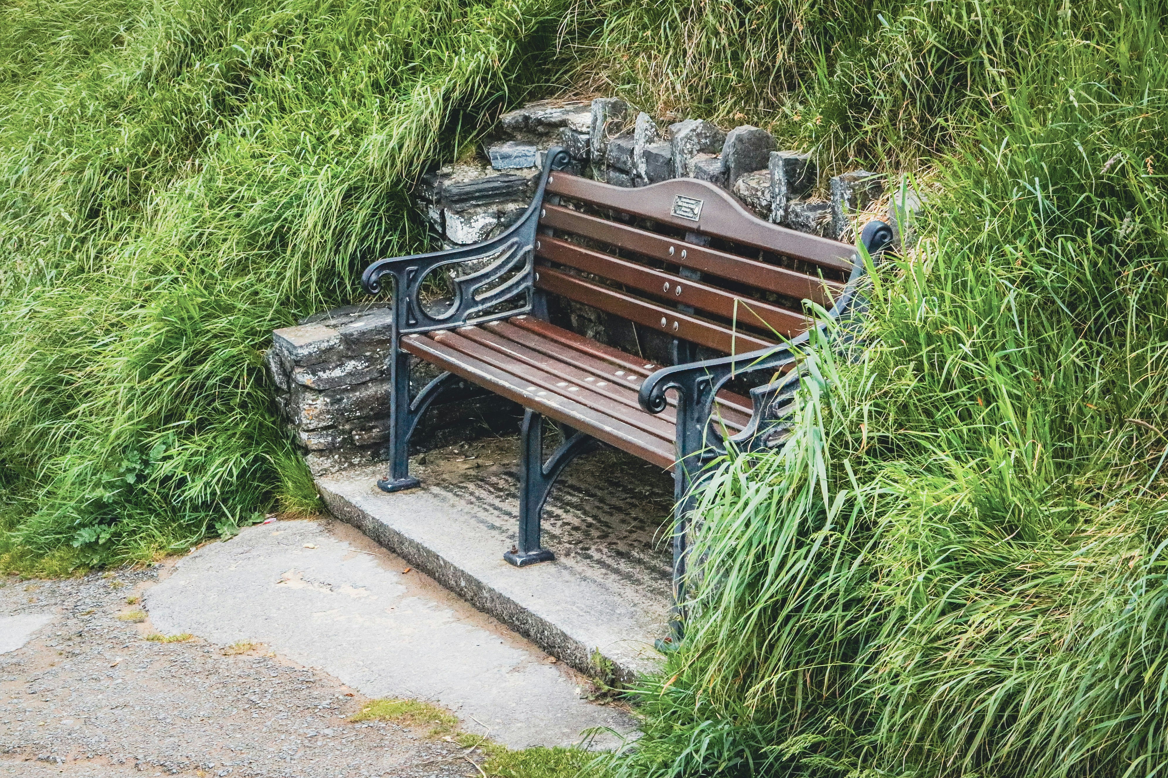 A wooden park bench nestled in green grass and stone.