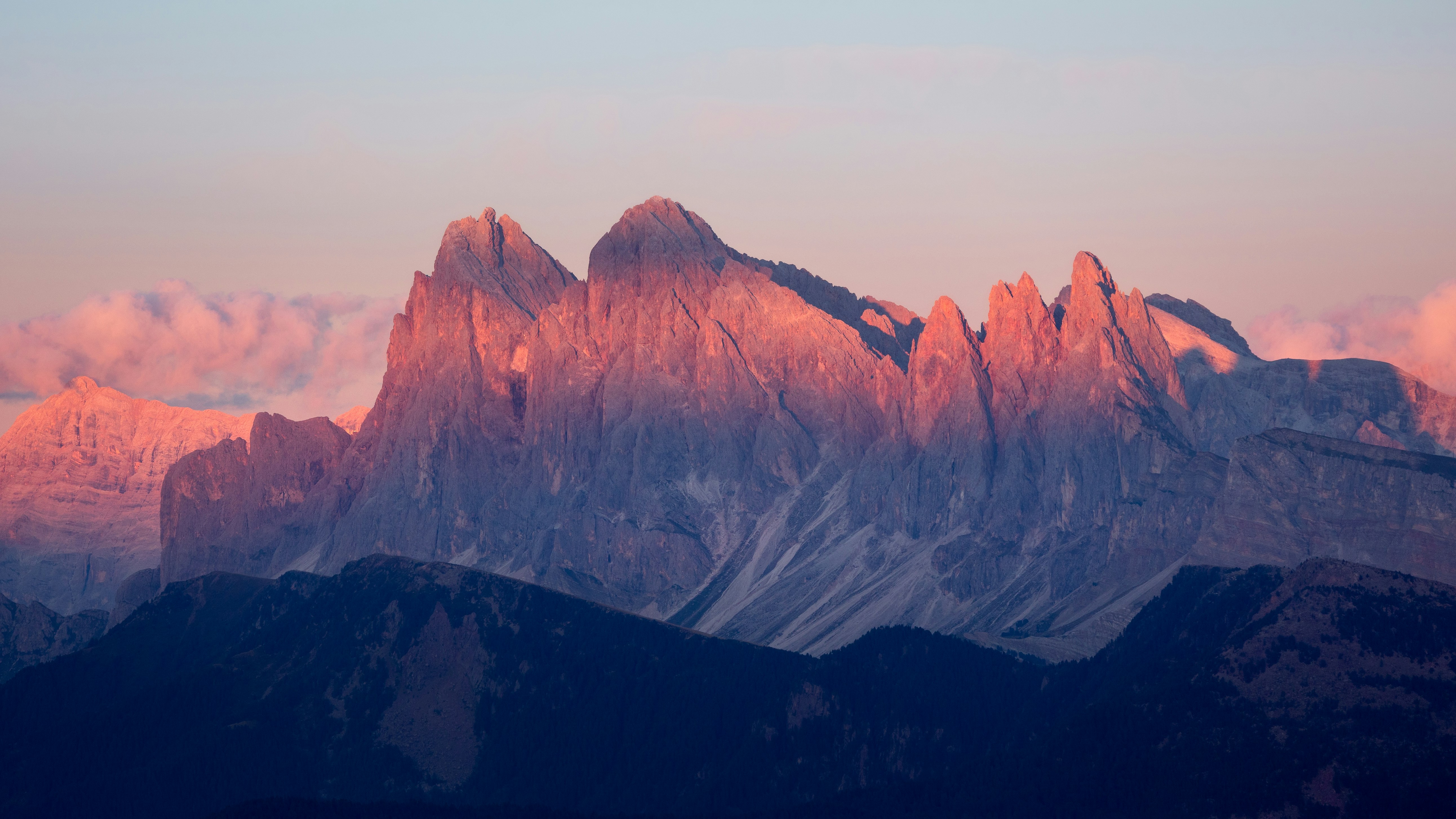 Dramatic mountain peaks glowing pink and orange at sunset.