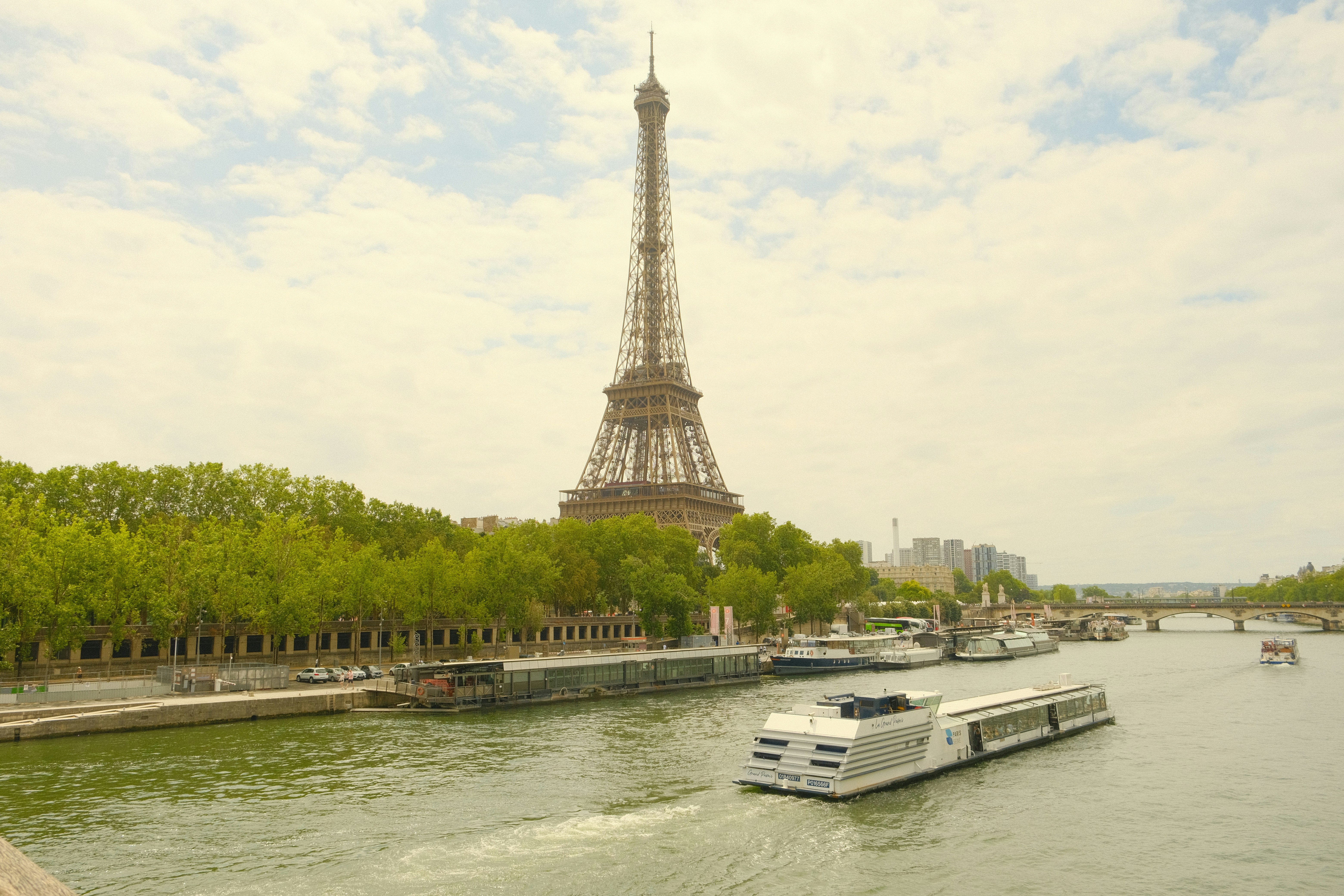 The eiffel tower overlooks a boat on the seine river.