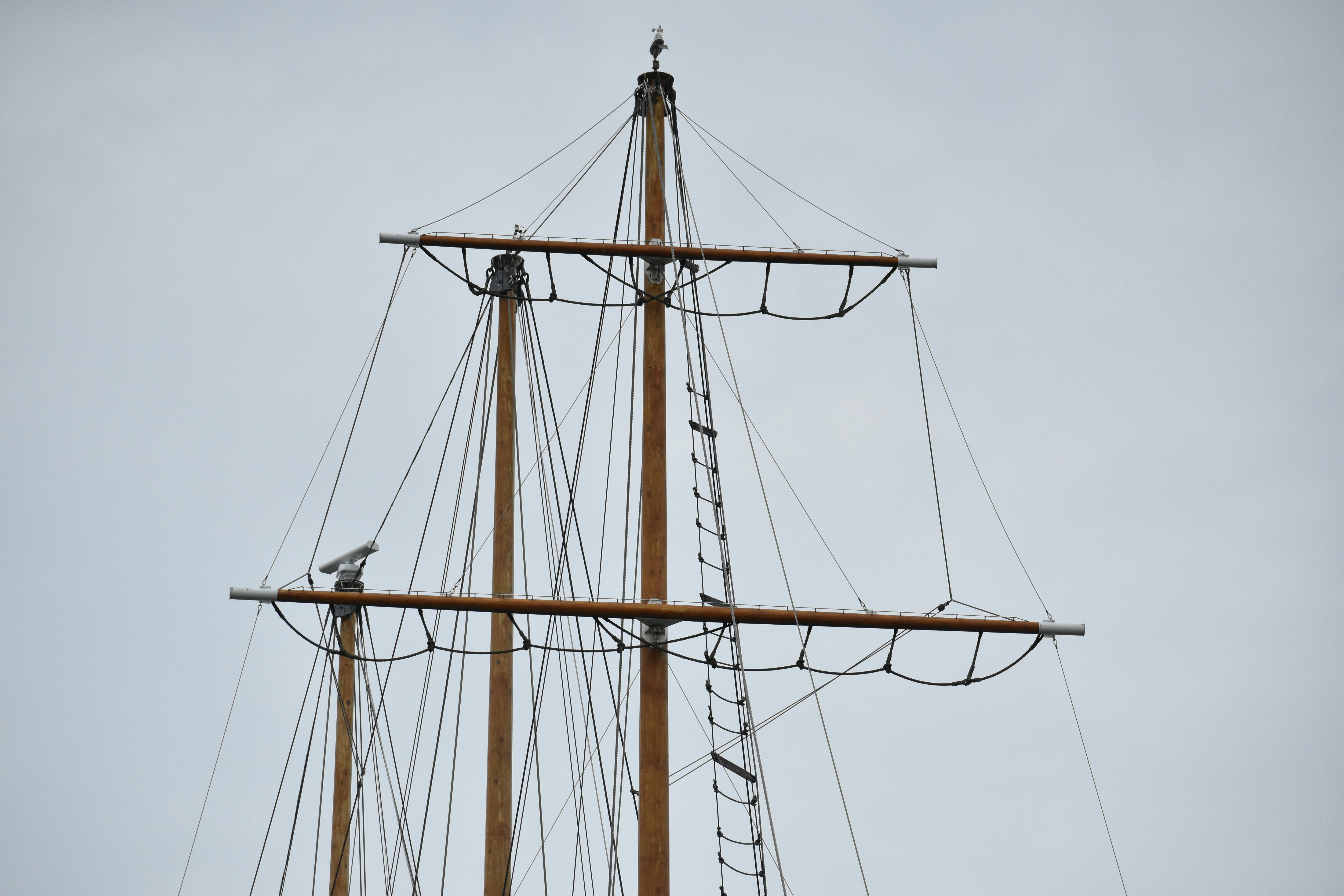 Tall wooden masts and intricate rigging of a sailing ship.