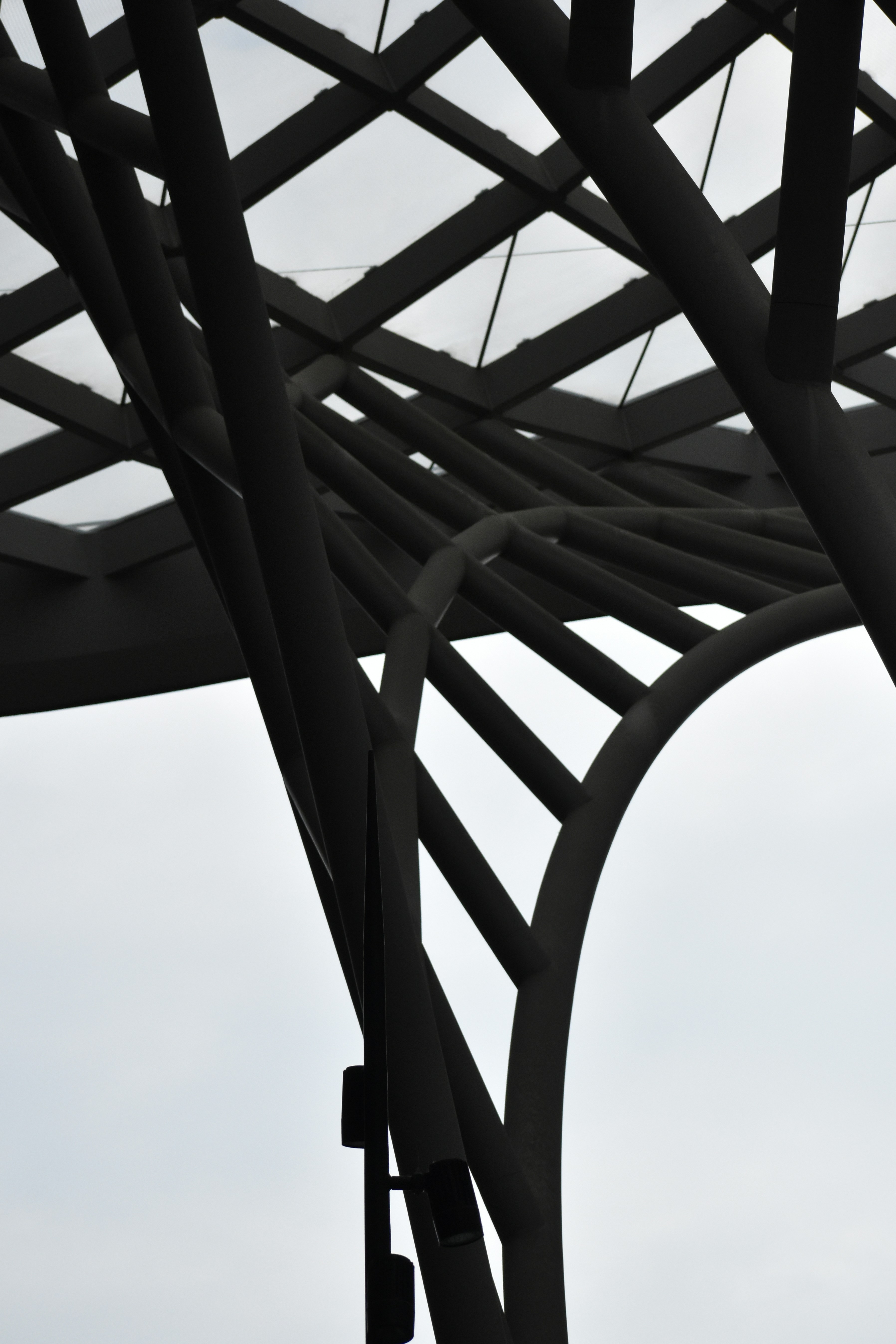 Abstract dark architectural structure against a bright sky.