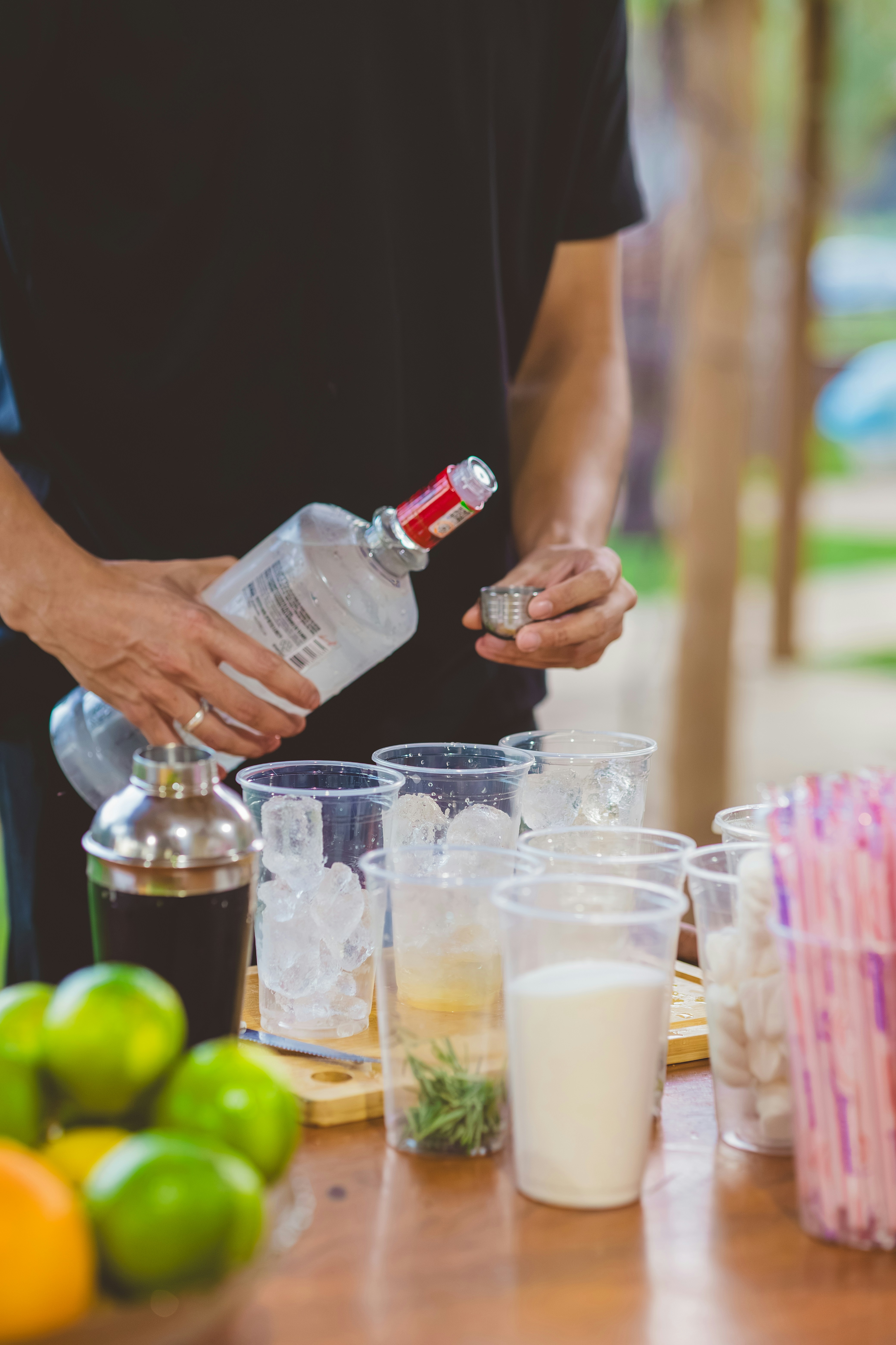 A person pouring alcohol into cups for cocktails.