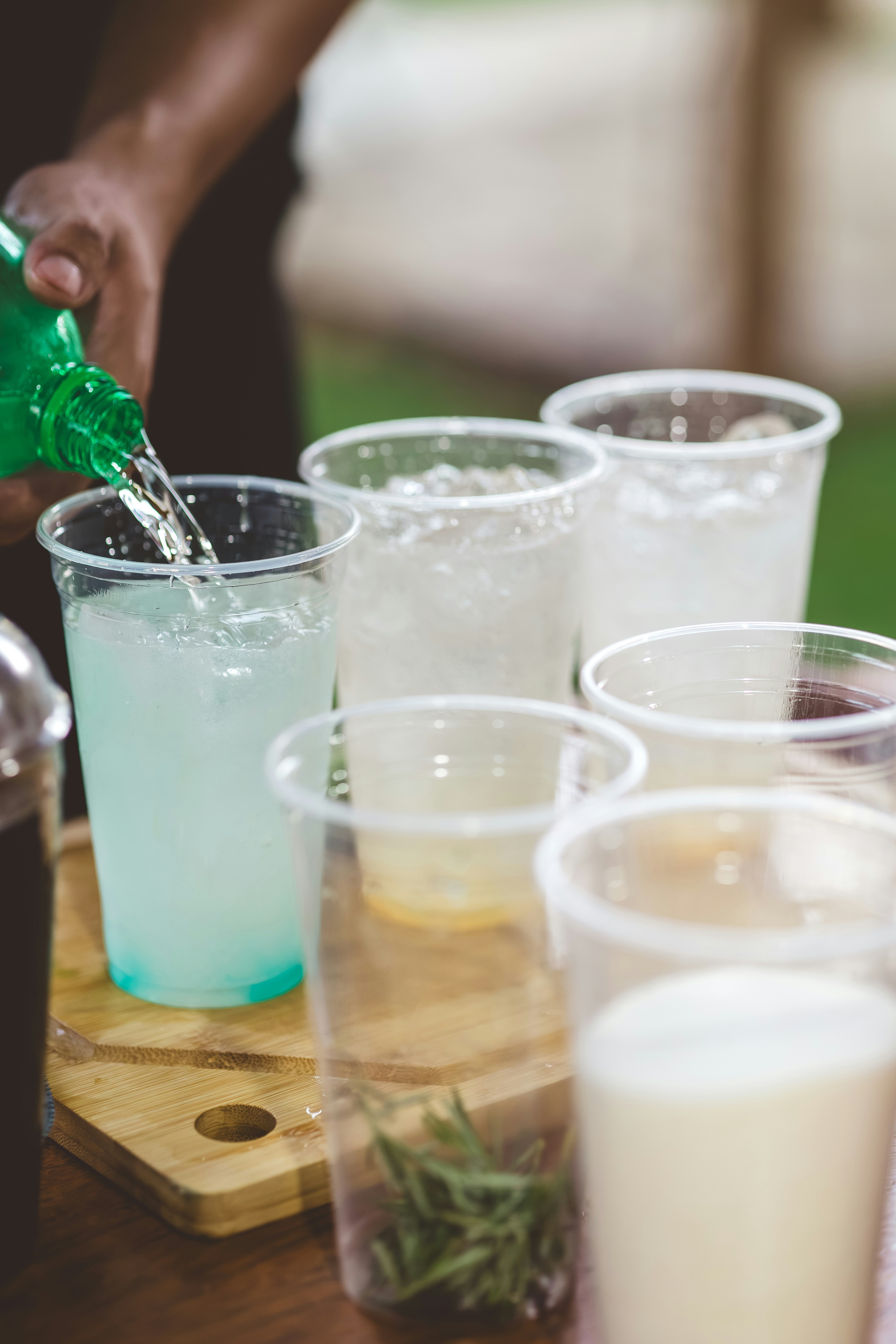 A hand pours a drink into a plastic cup.