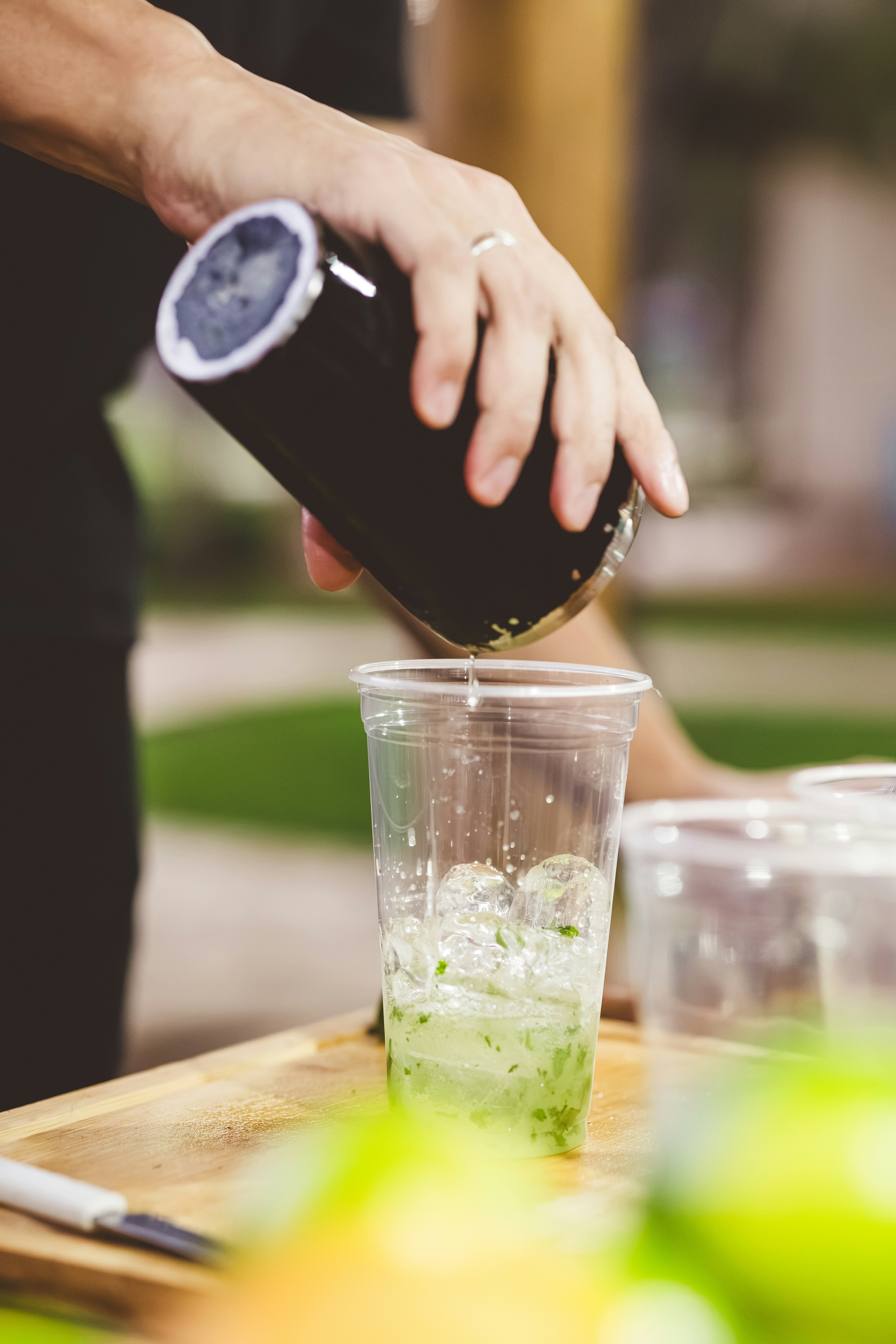 Hand pouring dark liquid into a cup with green mixture.