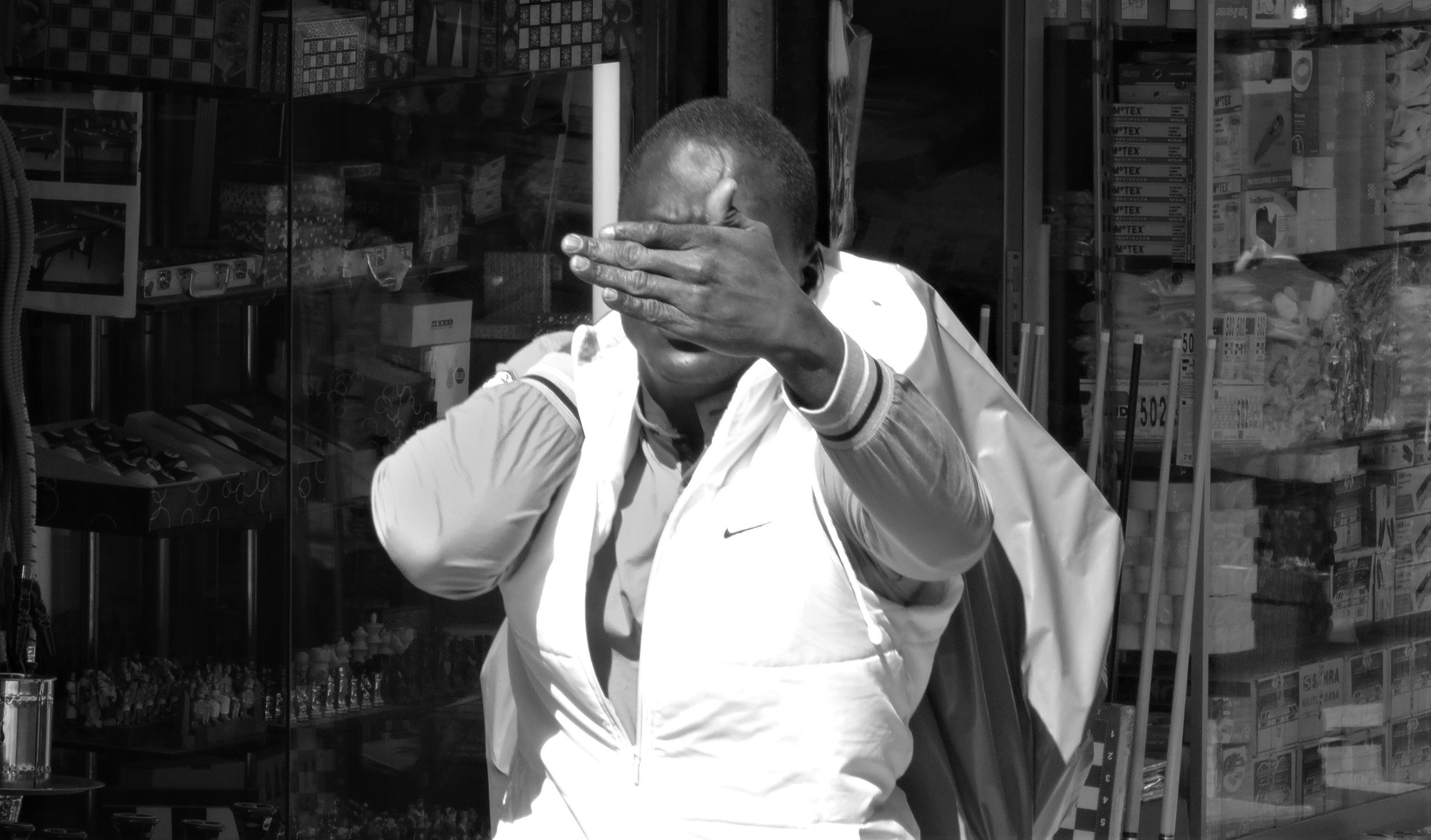 Man covering his face with hand, black and white.
