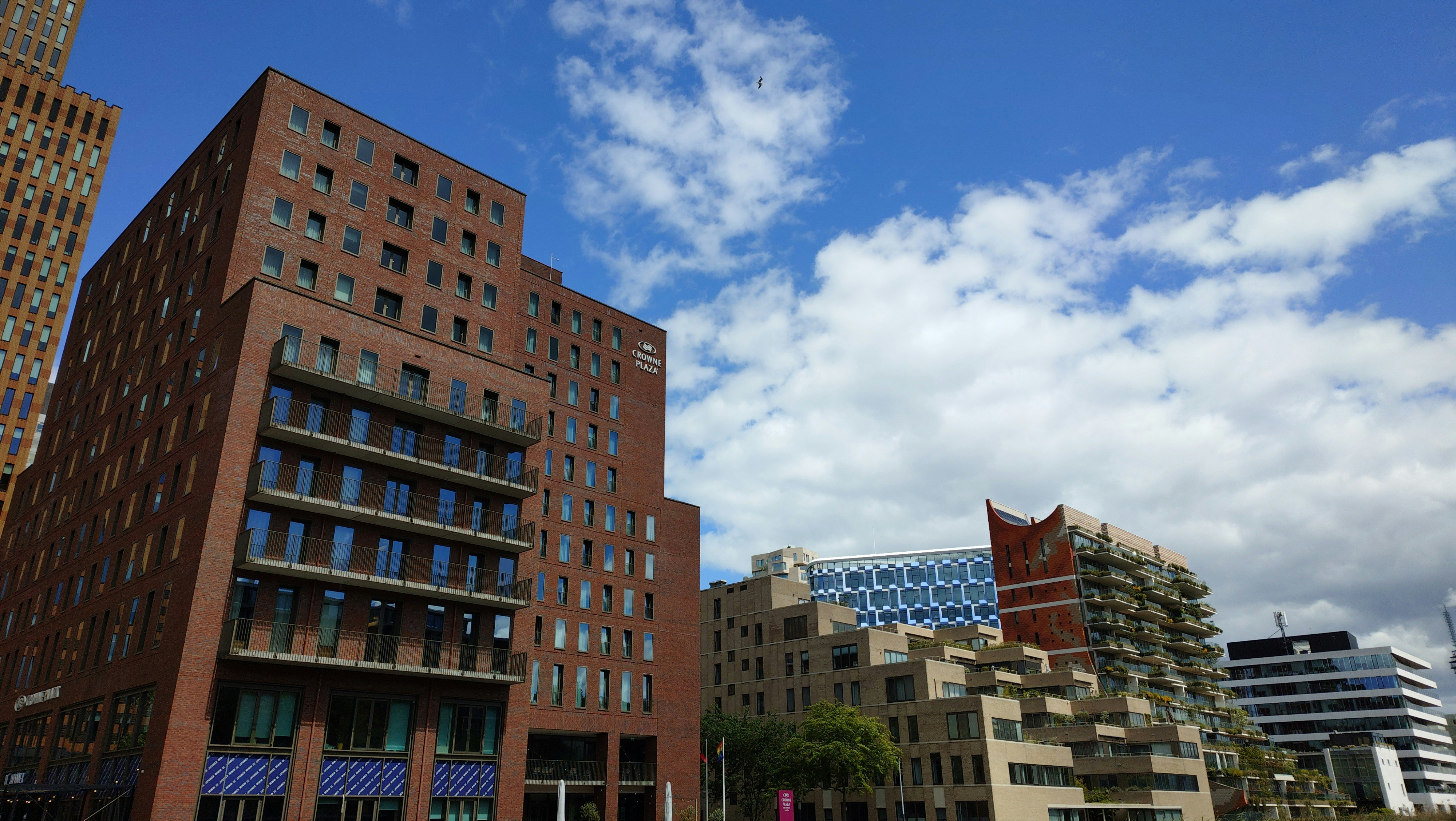 Modern brick buildings under a blue sky with clouds.