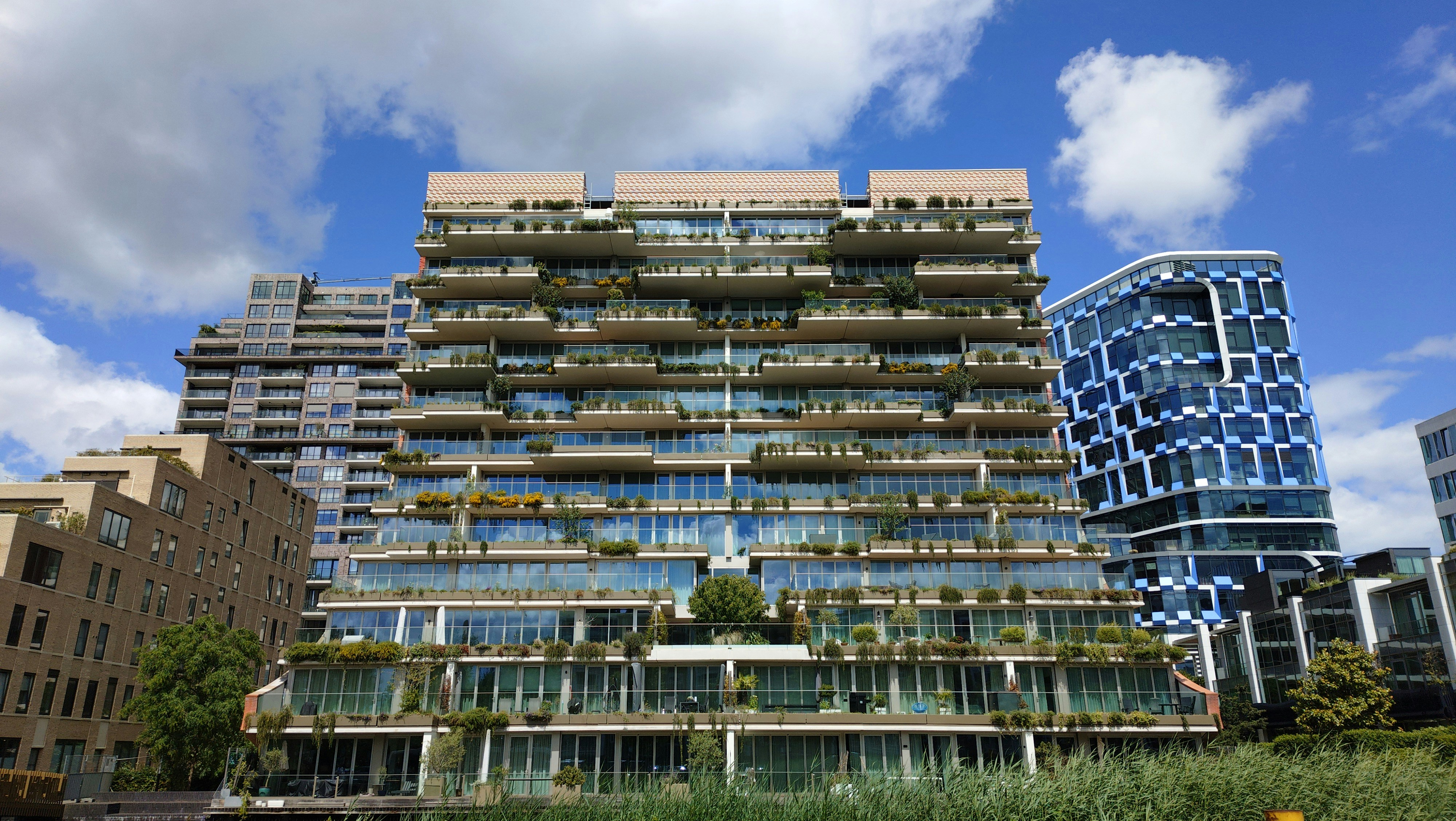Modern building with green balconies against a blue sky.