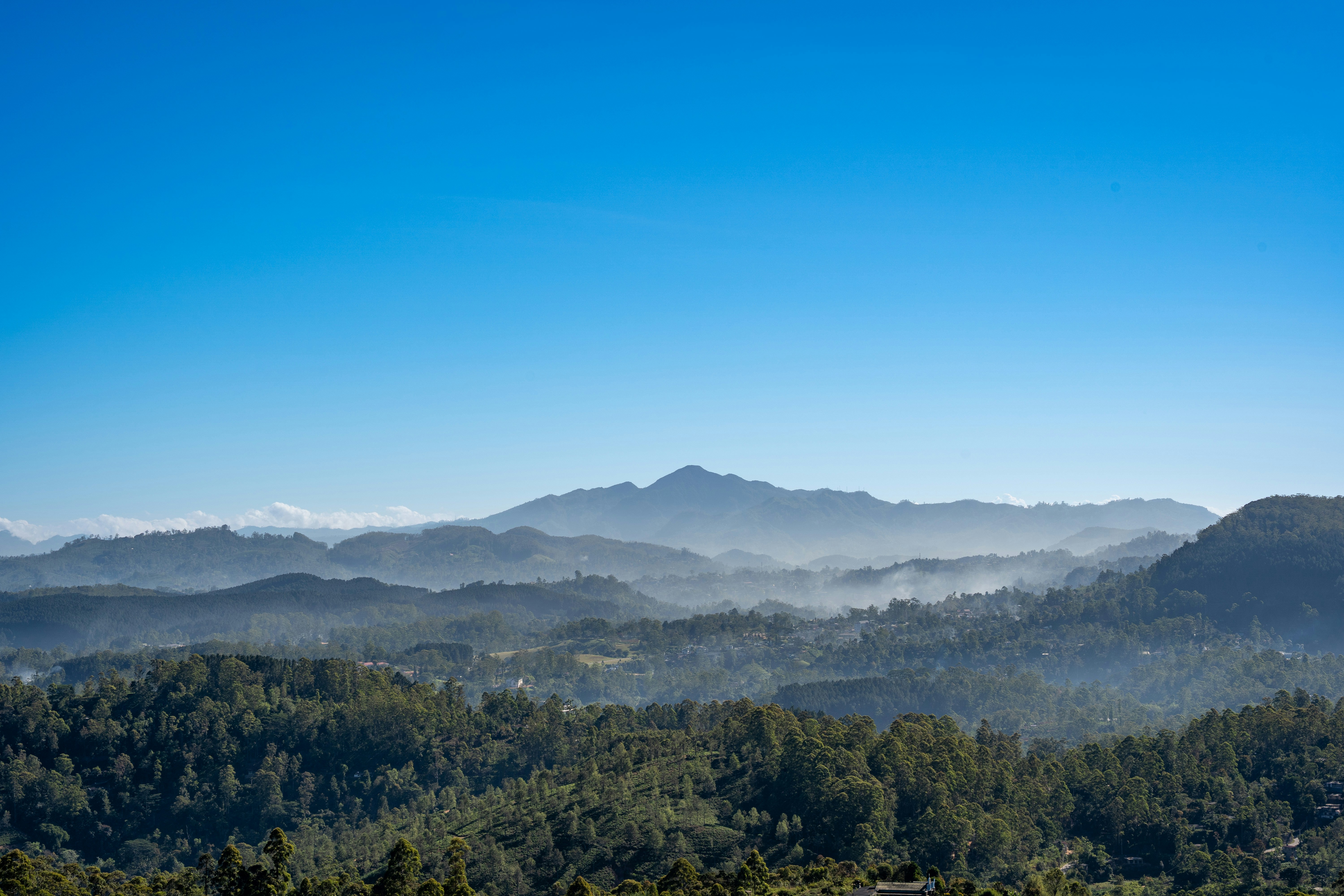 Layers of forested mountains under a clear blue sky.