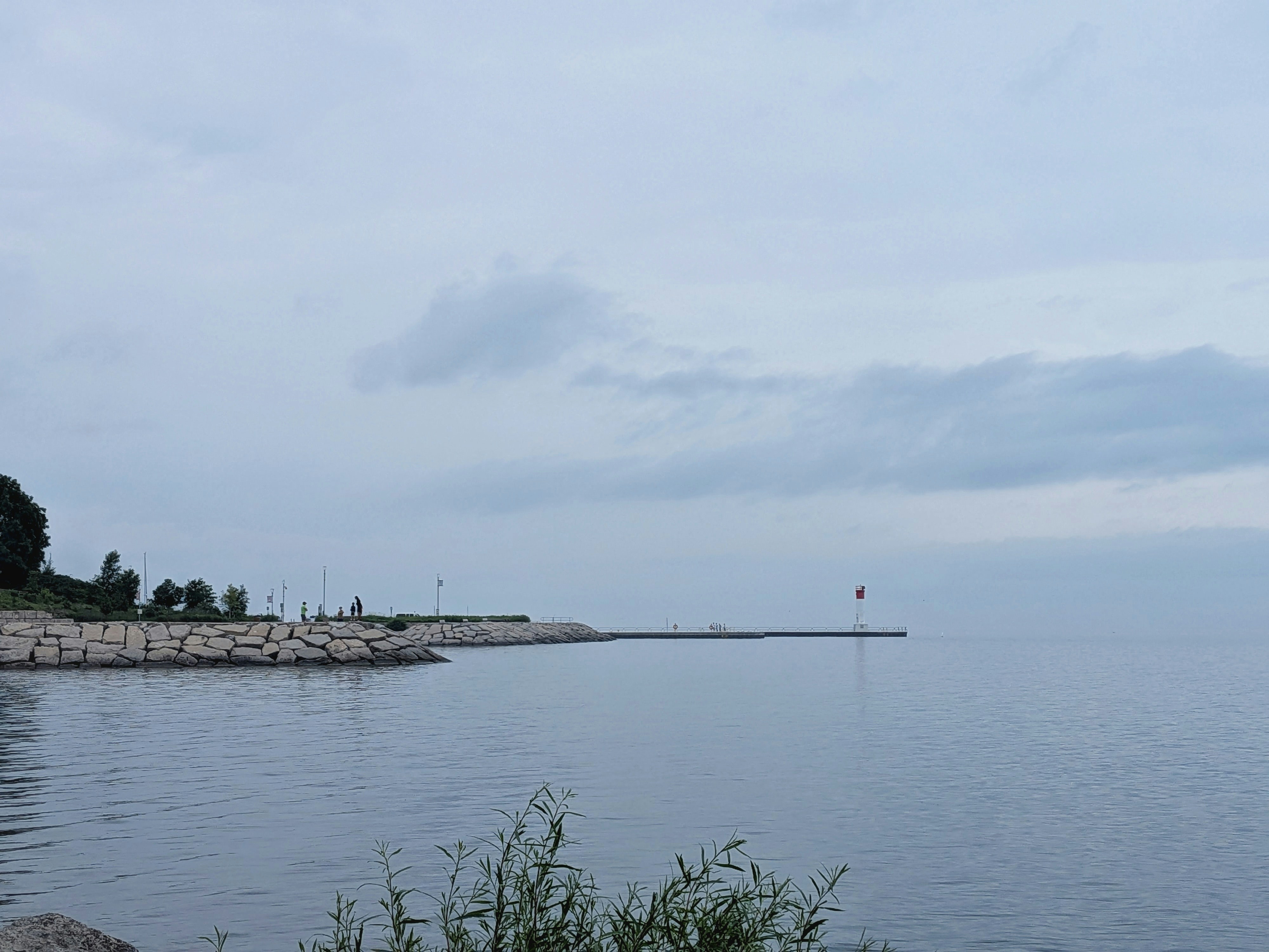 Calm lake with a rocky shore under an overcast sky.