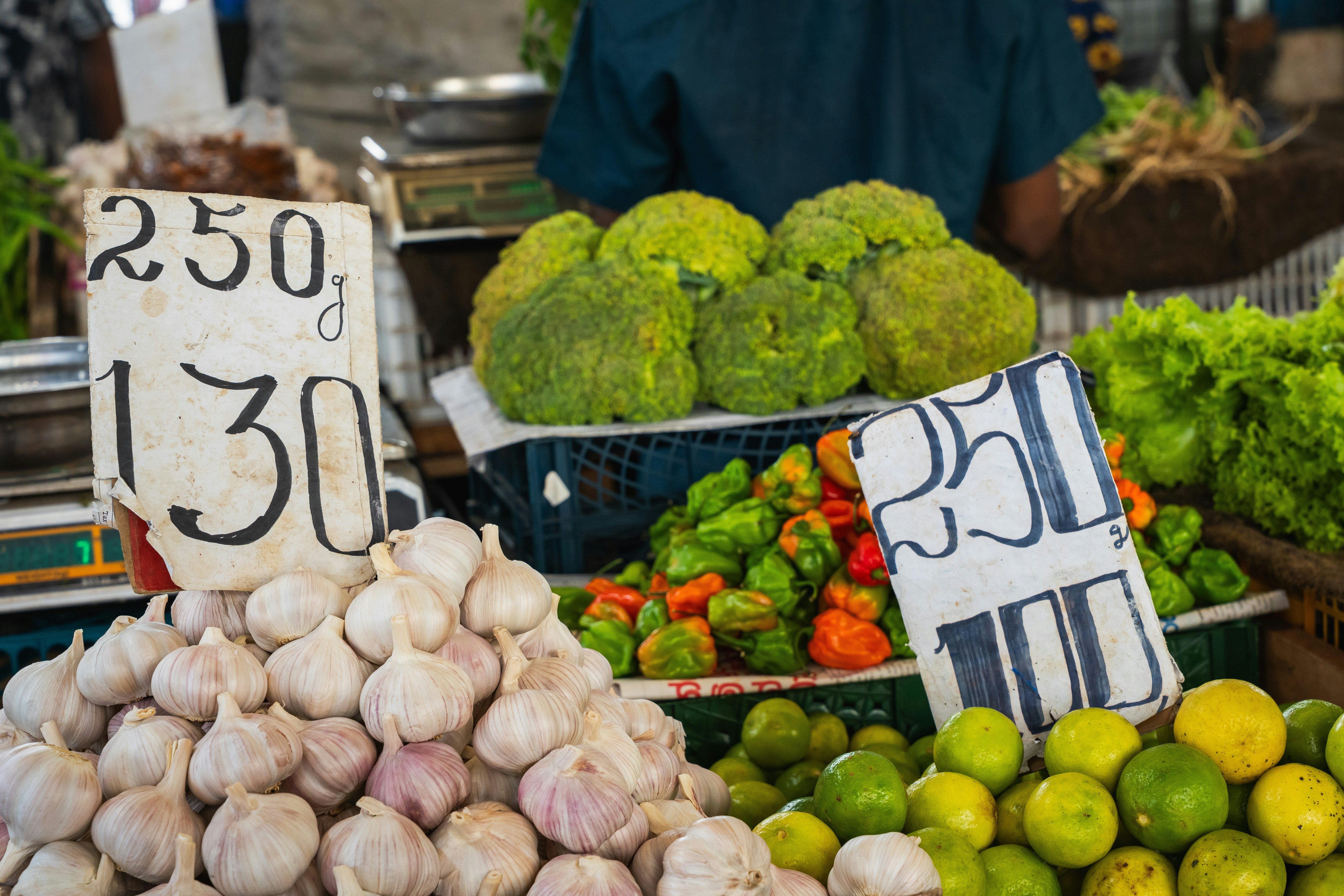Puesto de mercado vibrante con ajo fresco, limas, pimientos y verduras.