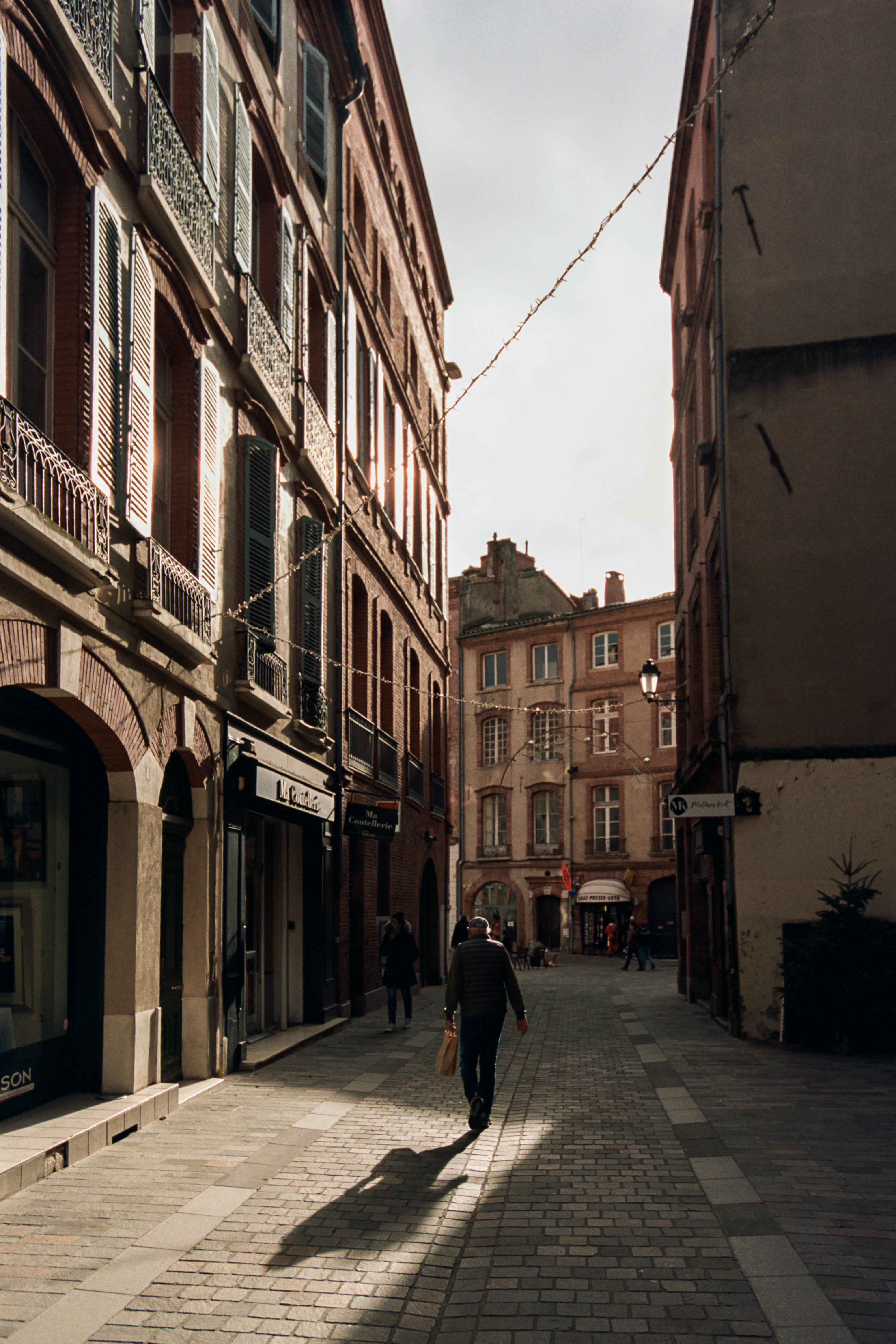 Sunlight casts long shadows on an old european city street.